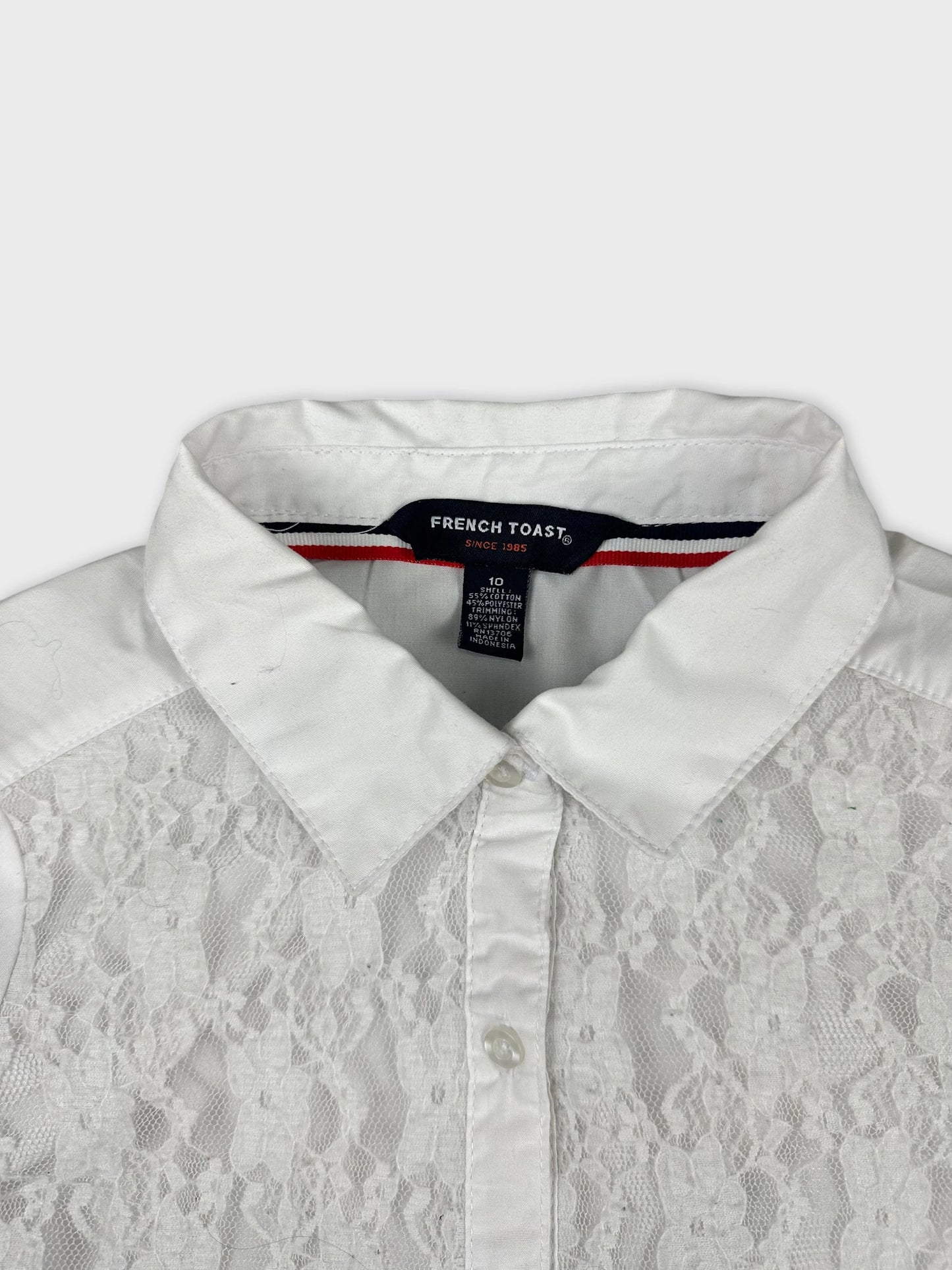 Detail view of a white women's shirt featuring lace panels and a classic collar.