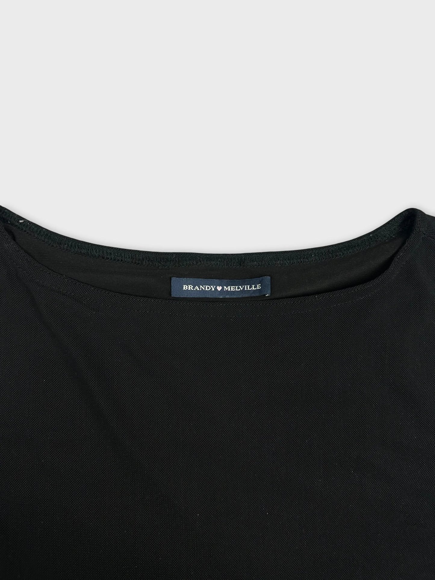 Detail view of a black short sleeve top featuring a textured fabric pattern.