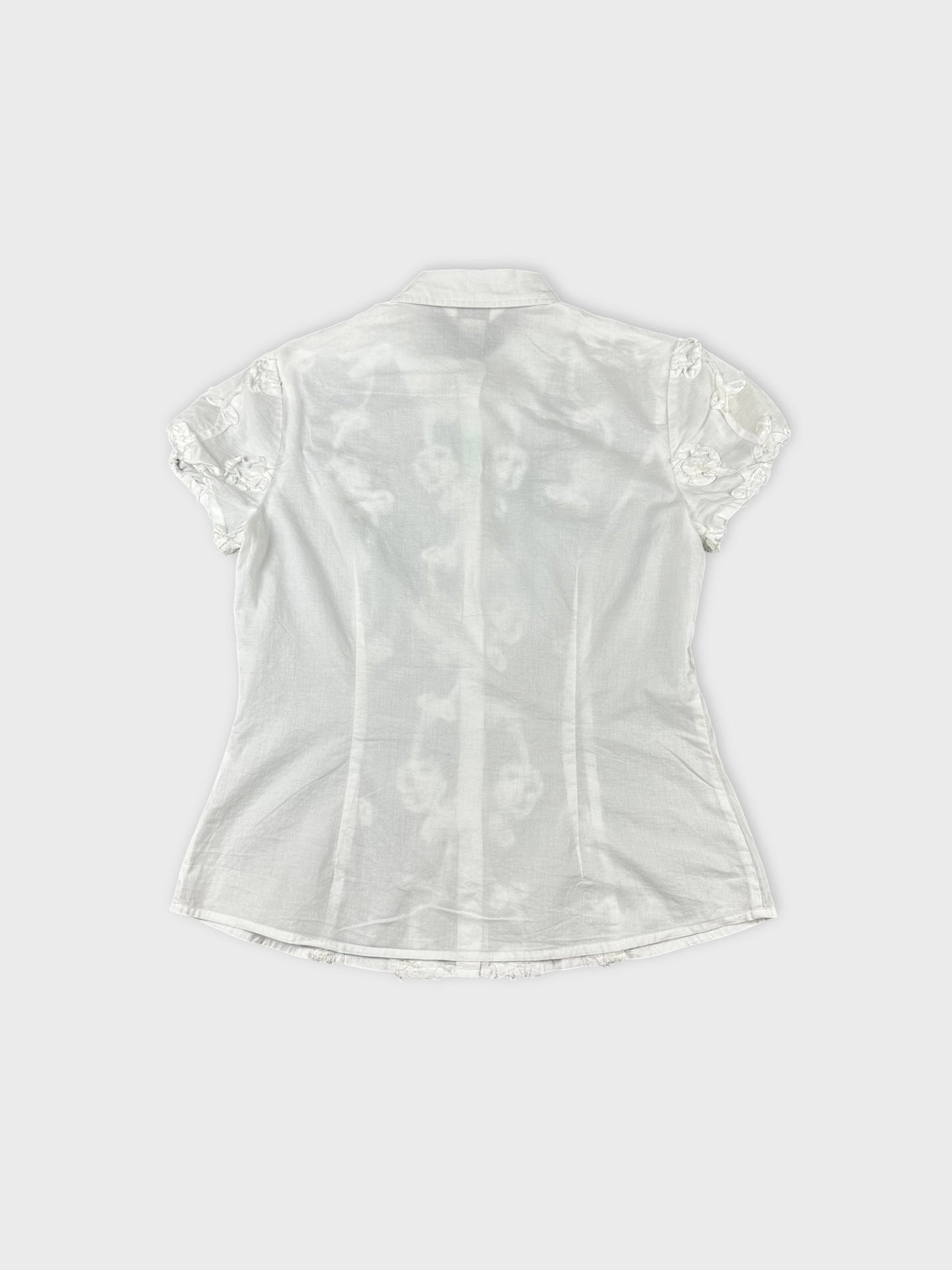Back view of a white short sleeve top with floral trim.