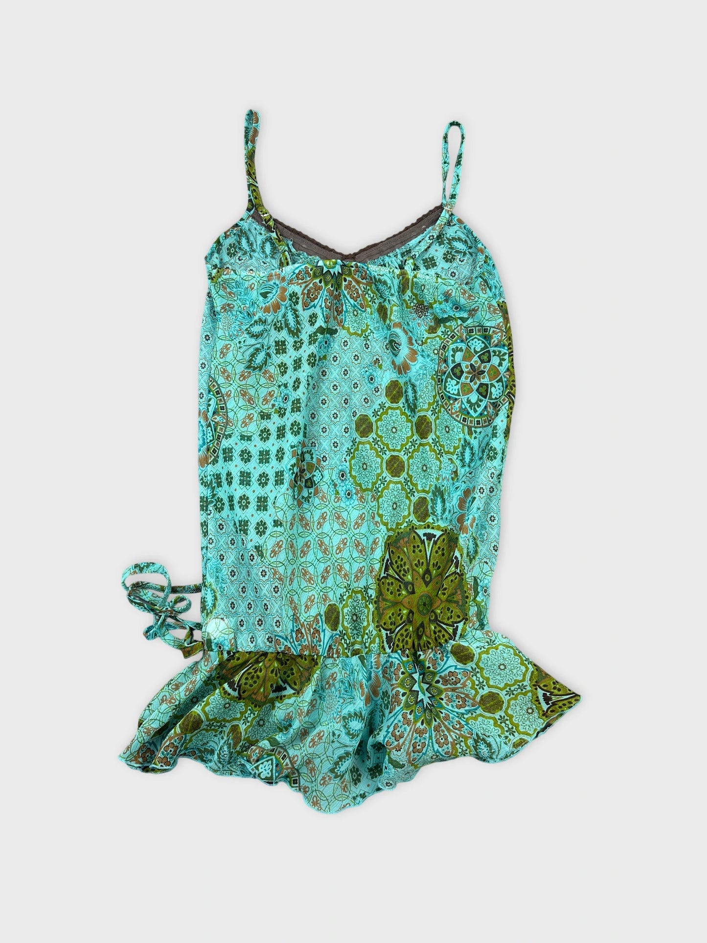 Back view of a turquoise sleeveless top with floral patterns.