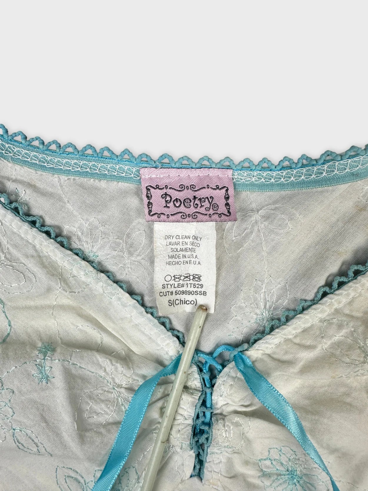 detail view of women’s short sleeve top with light gray fabric and blue trim