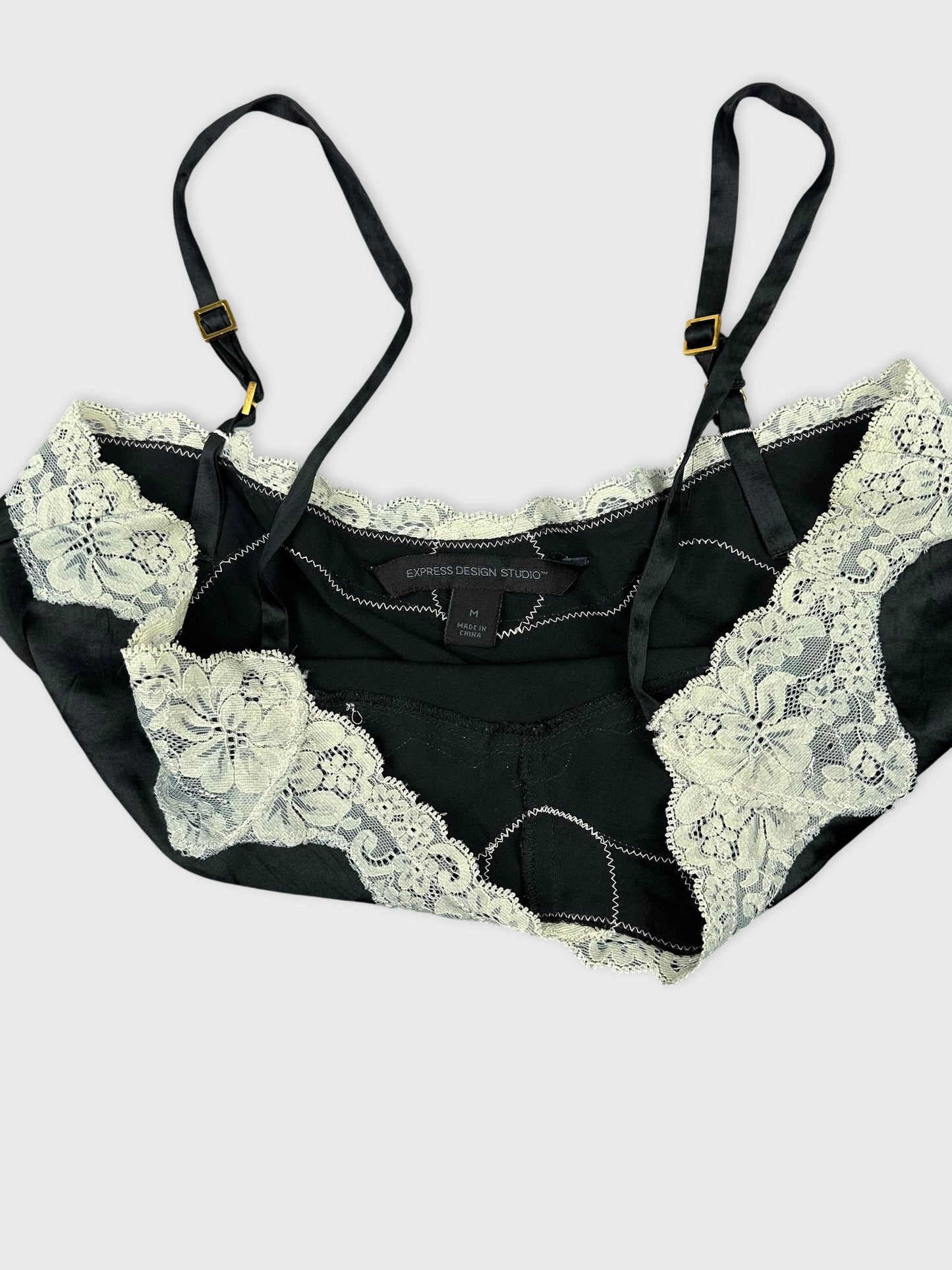 Detail view of a black top featuring lace trim and adjustable straps.