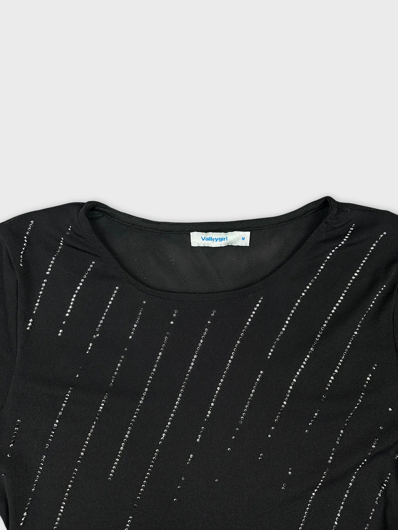 Detail view of a black short sleeve top with sequined lines.