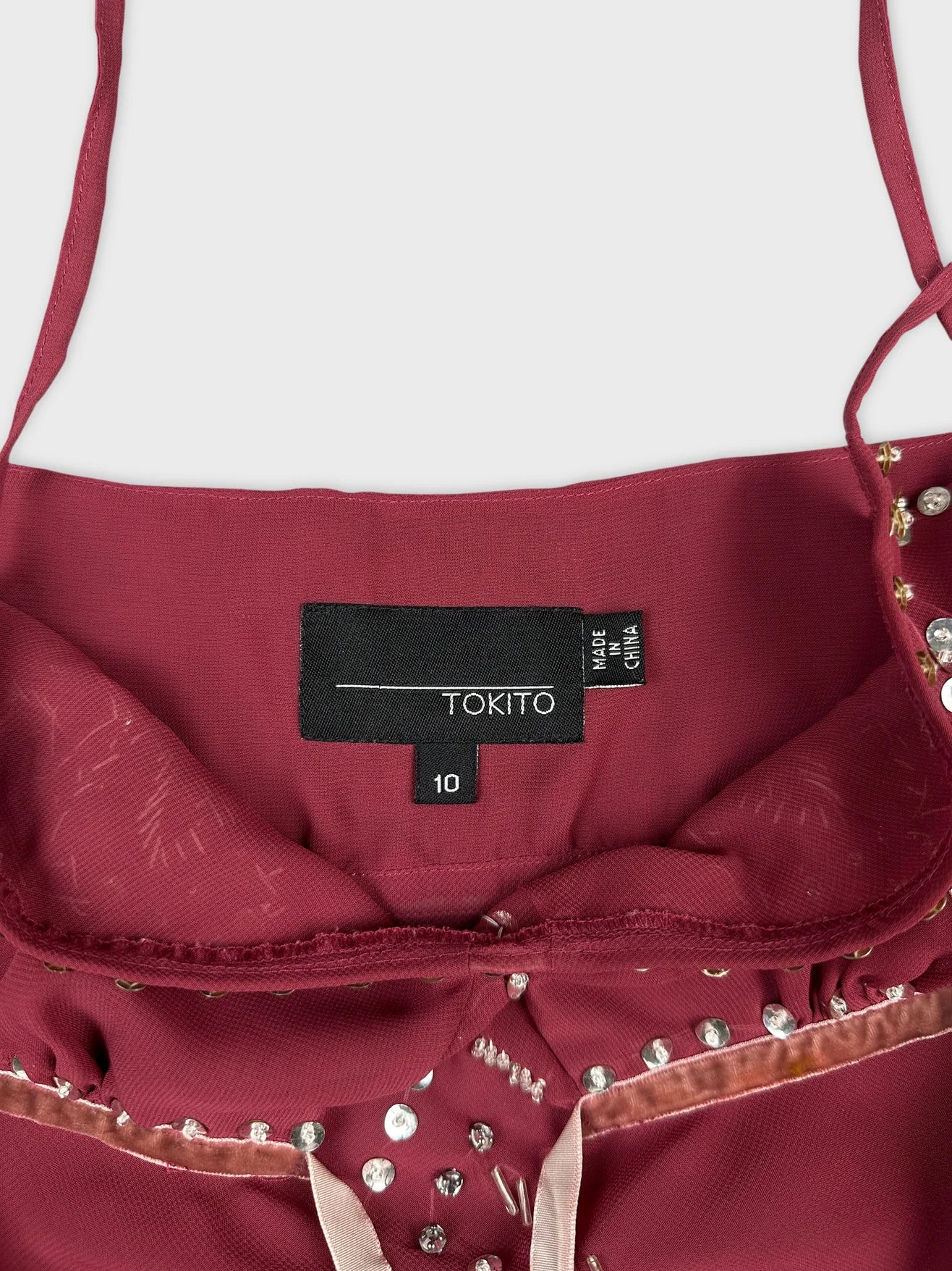 Detail view of a burgundy sleeveless top with embellishments.