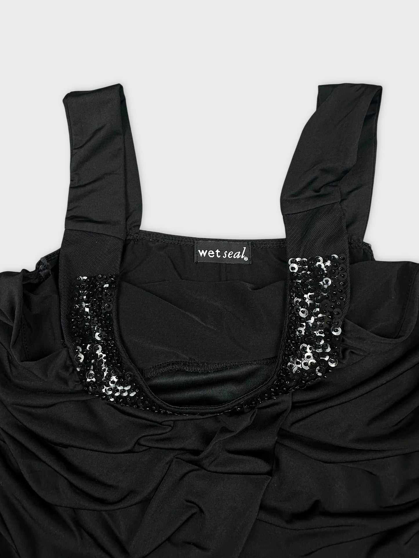 detail view of black women's top with sequined trim and gathered fabric.