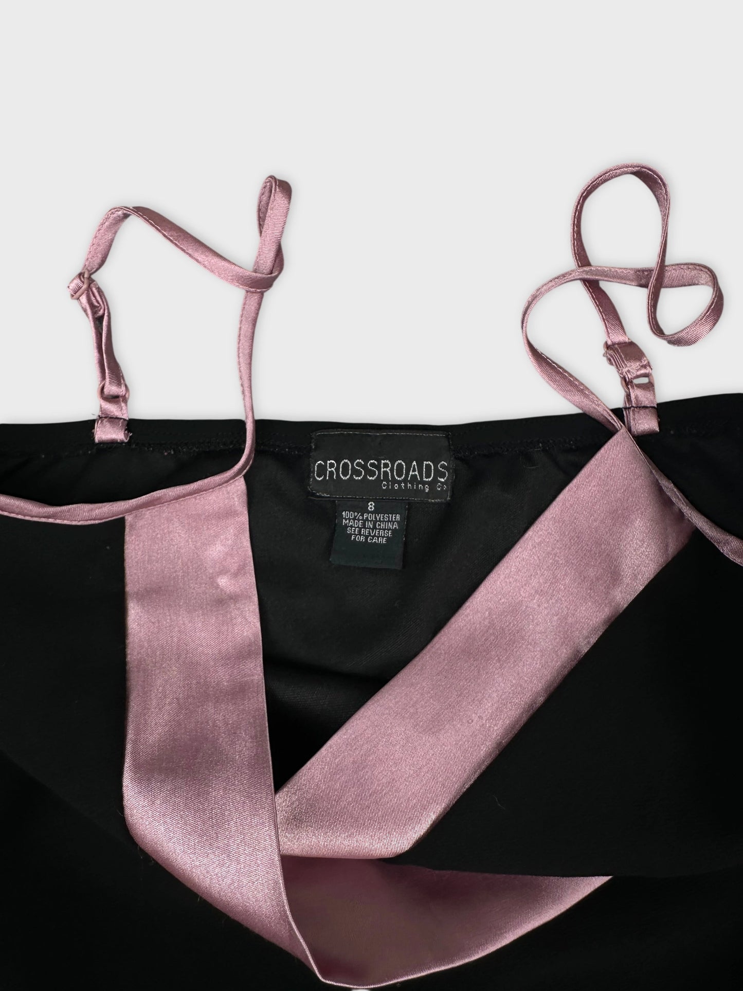 Detail view of a black top with pink satin straps