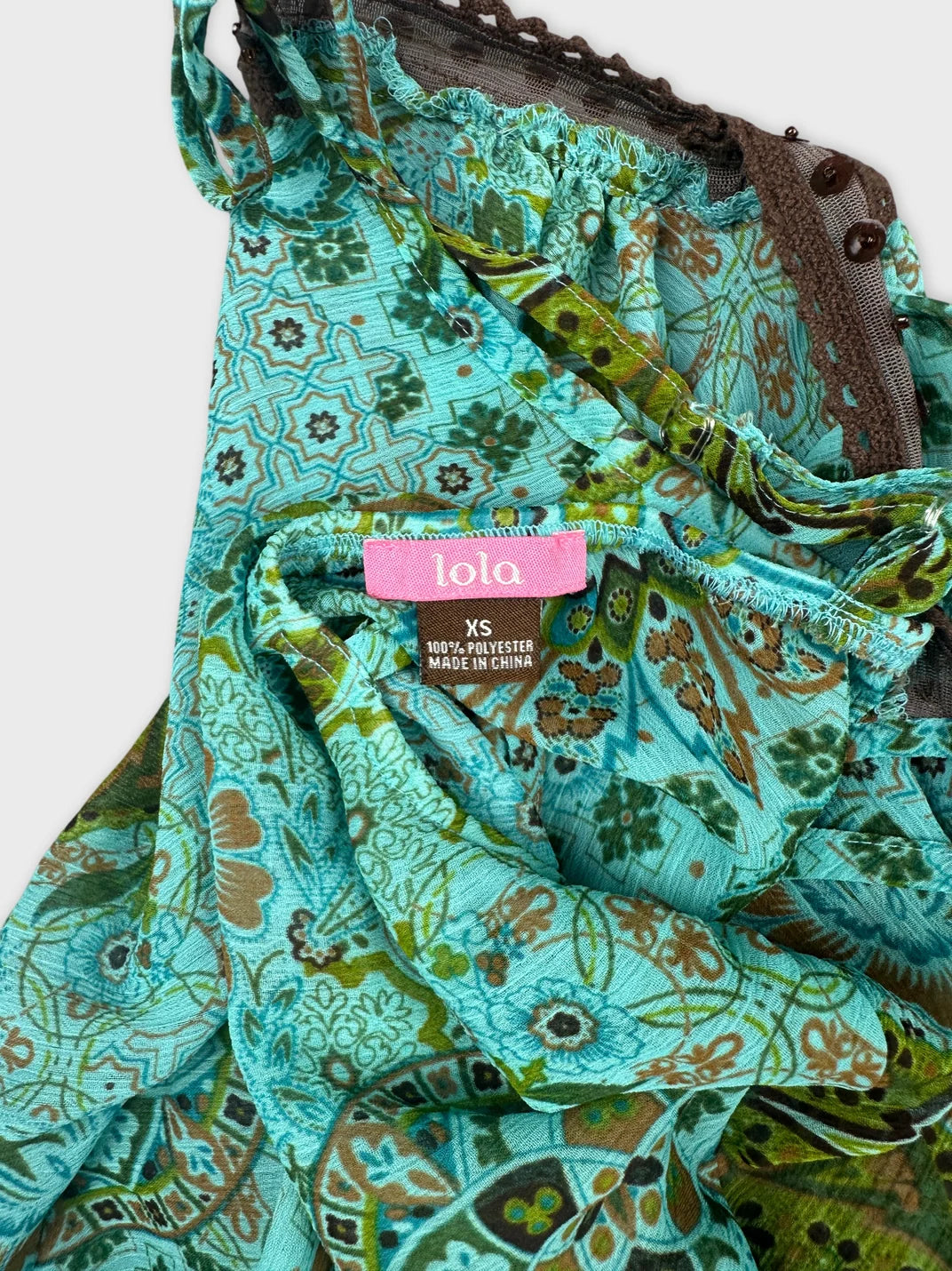 Detail view of a turquoise women's top featuring a floral pattern.