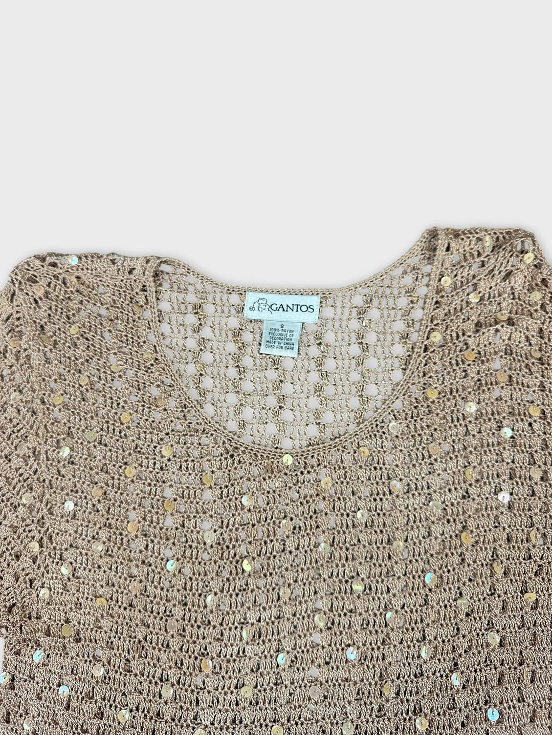 Detail view of a light brown crochet top with sequin embellishments.