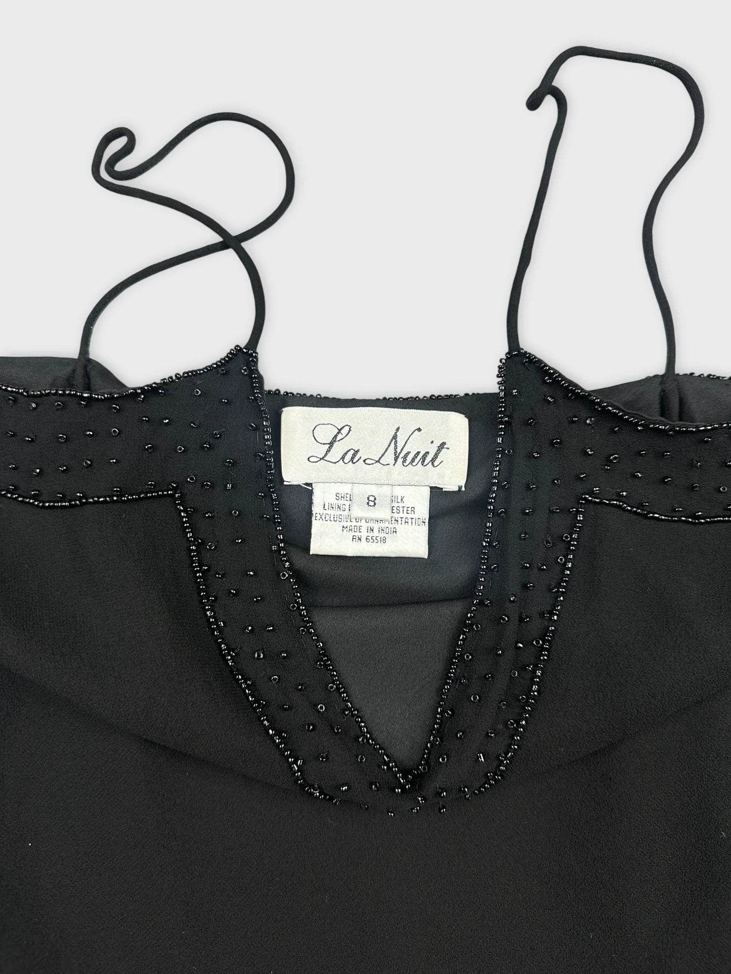 Black top shown in detail view with beaded neckline embellishment.