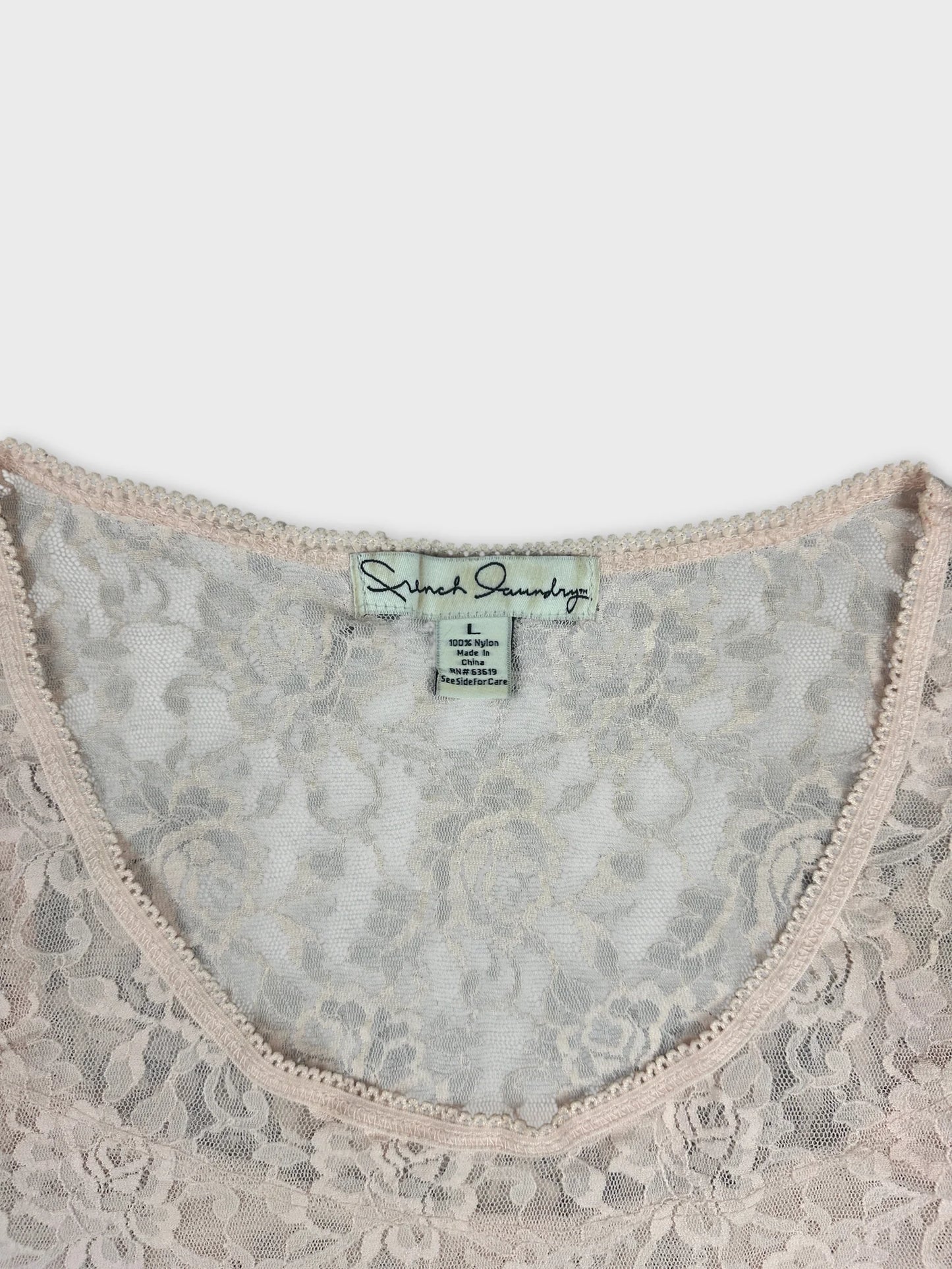Detail view of a lace women's top in soft pink with scalloped trim