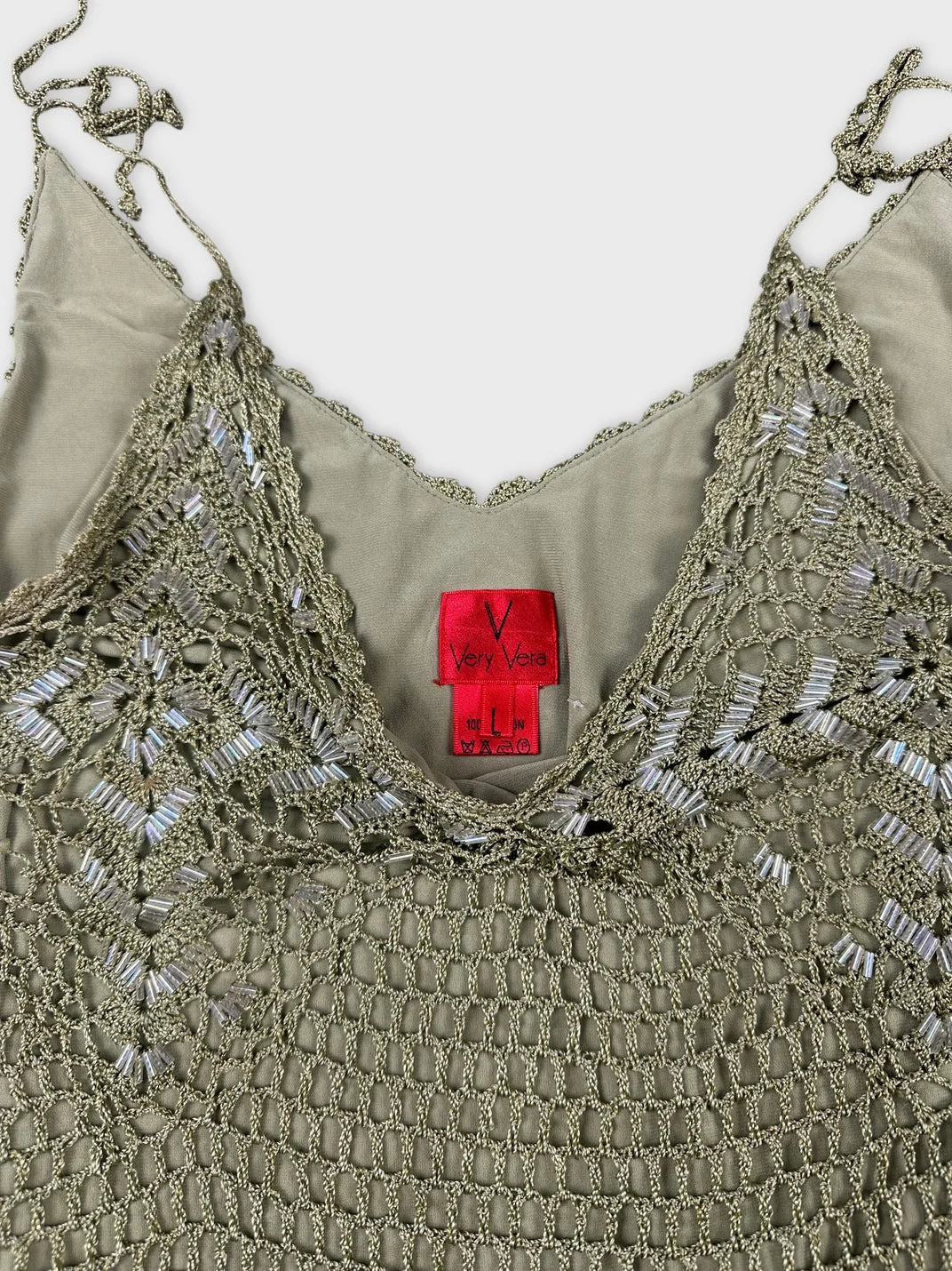 Detail view of a vintage women's sleeveless top in olive green with lace trim.