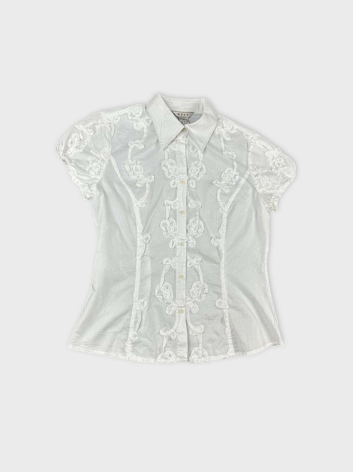 White short sleeve top with floral embroidery detail view.