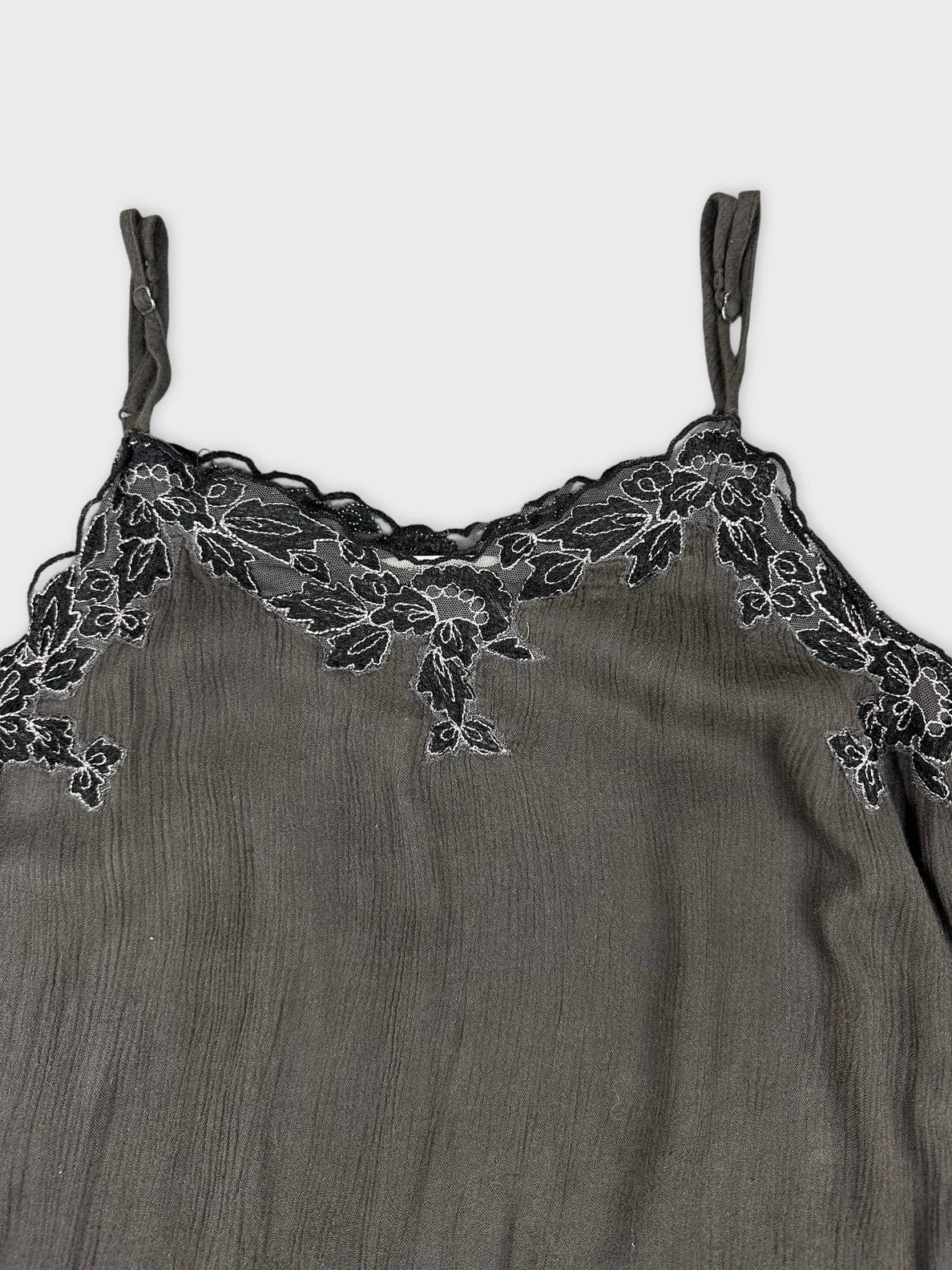 Detail view of a women's sleeveless top in dark gray with floral lace trim.