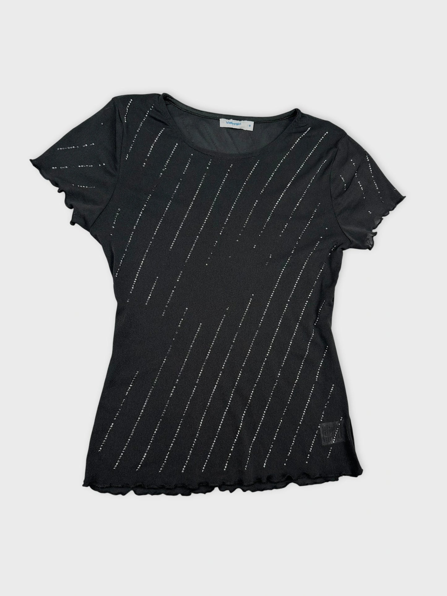 Detail view of a black short sleeve top with metallic linear embellishments.