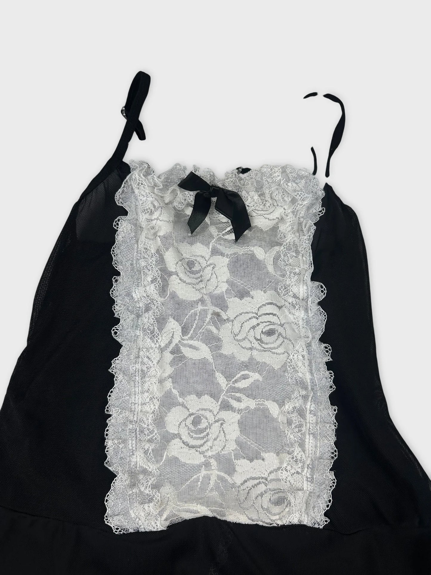 Detail view of a black sleeveless top with lace trim and bow.