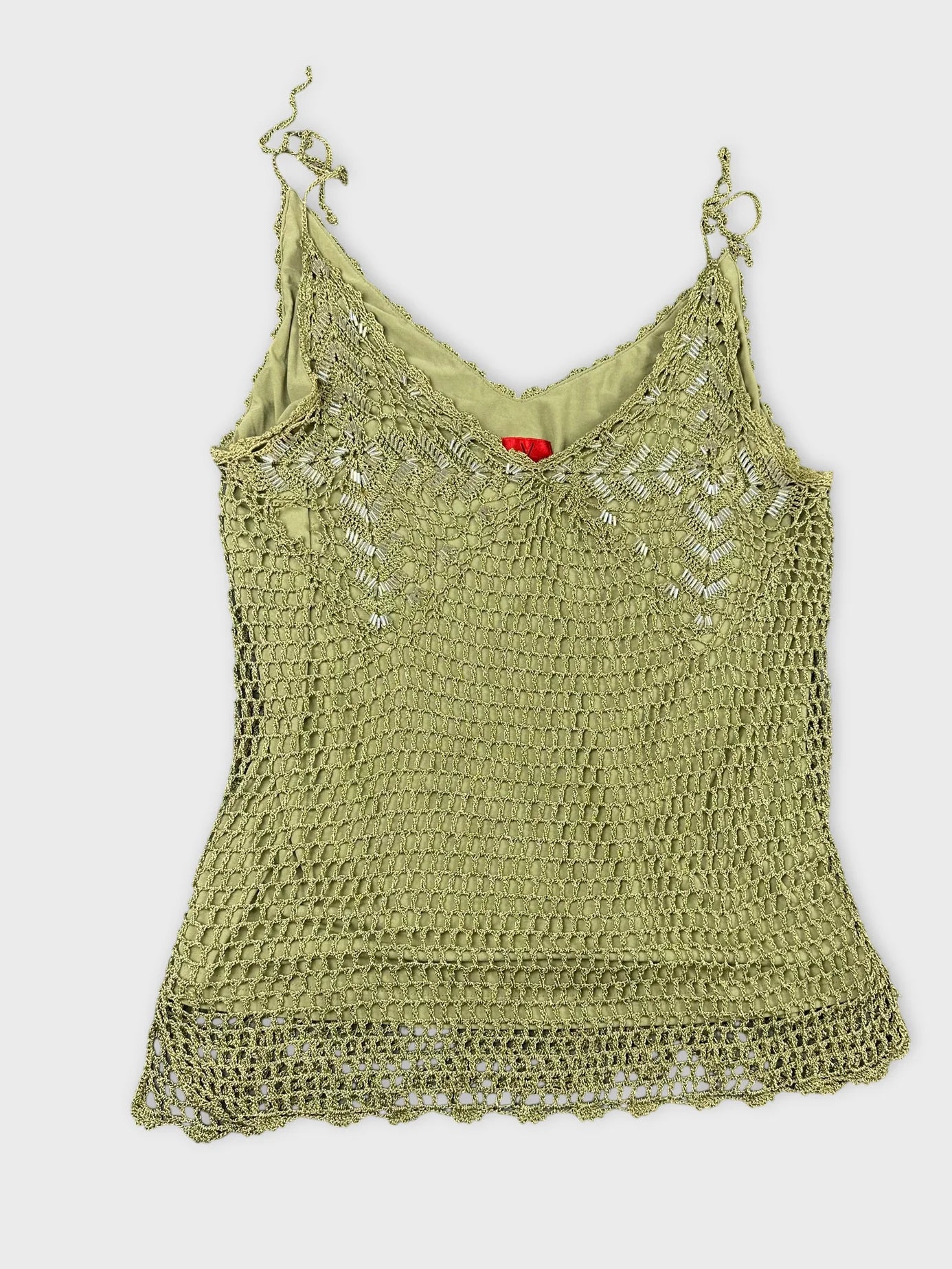Detail view of an olive green short sleeve top with crochet pattern.