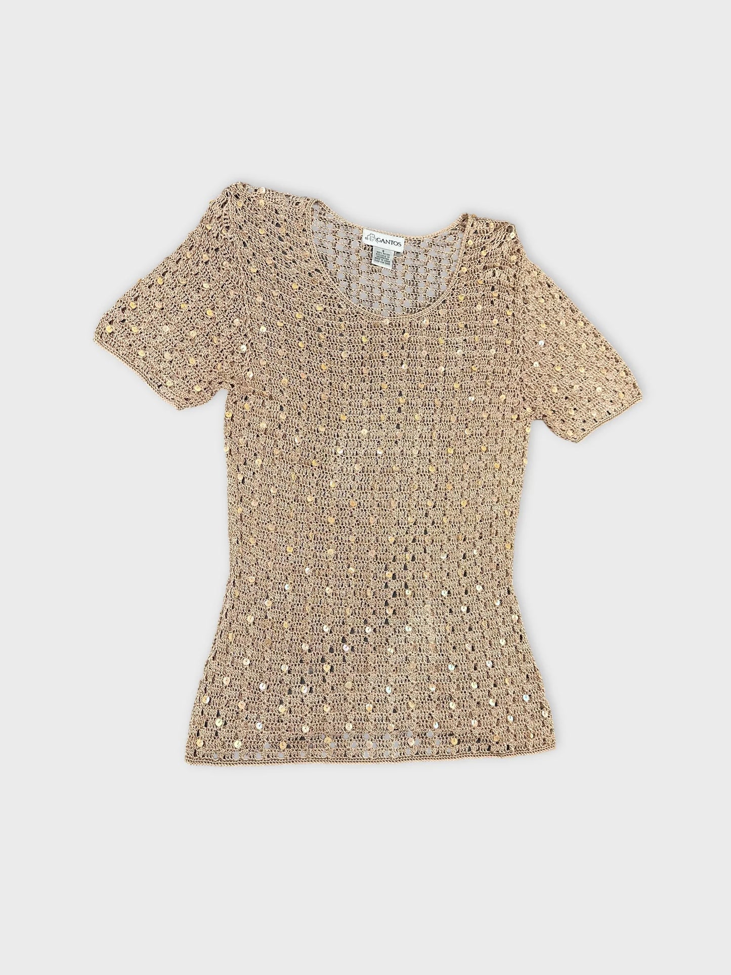 Detail view of a short sleeve top in beige with sequined pattern.