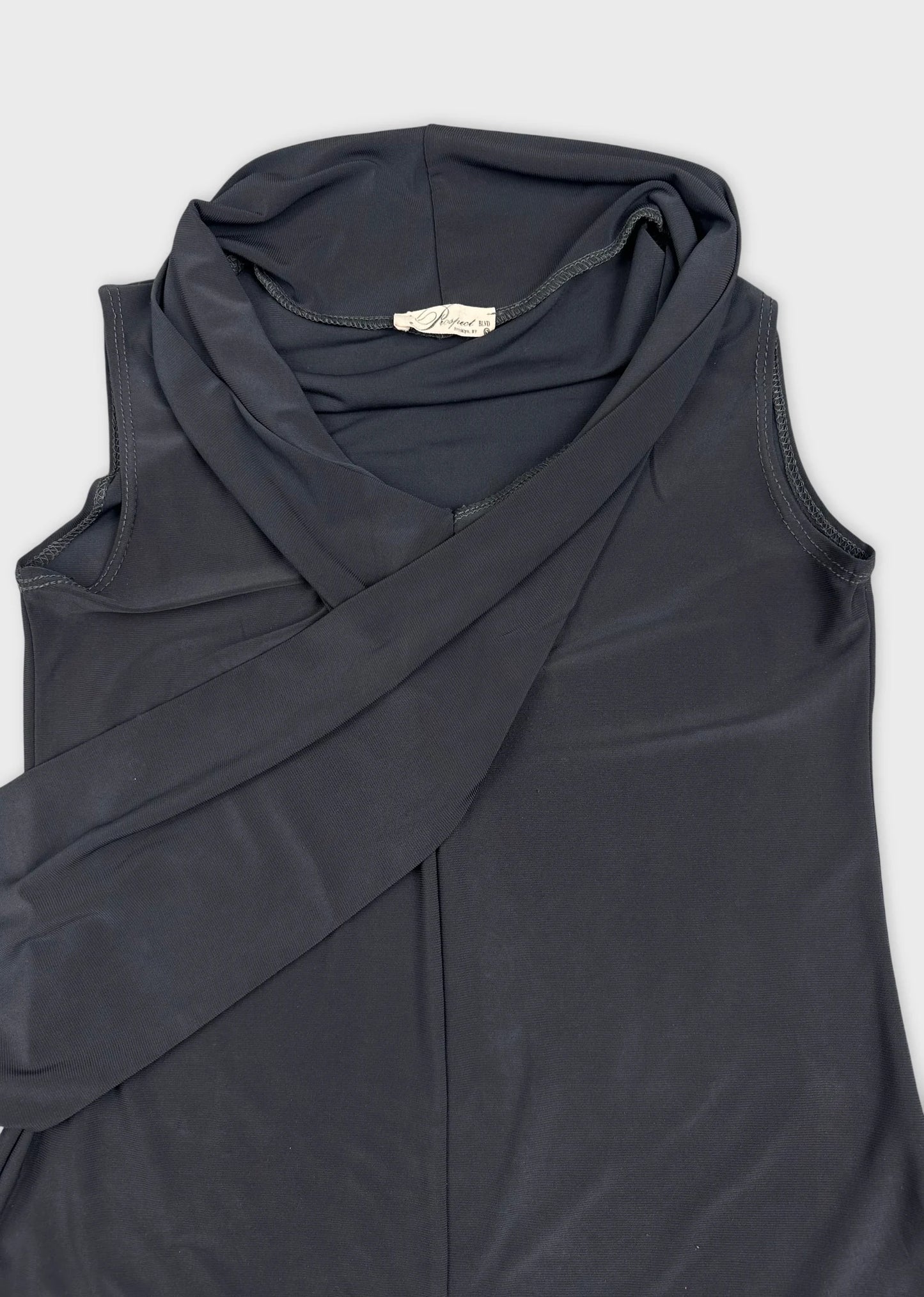Detail view of a black sleeveless top with a draped neck design.