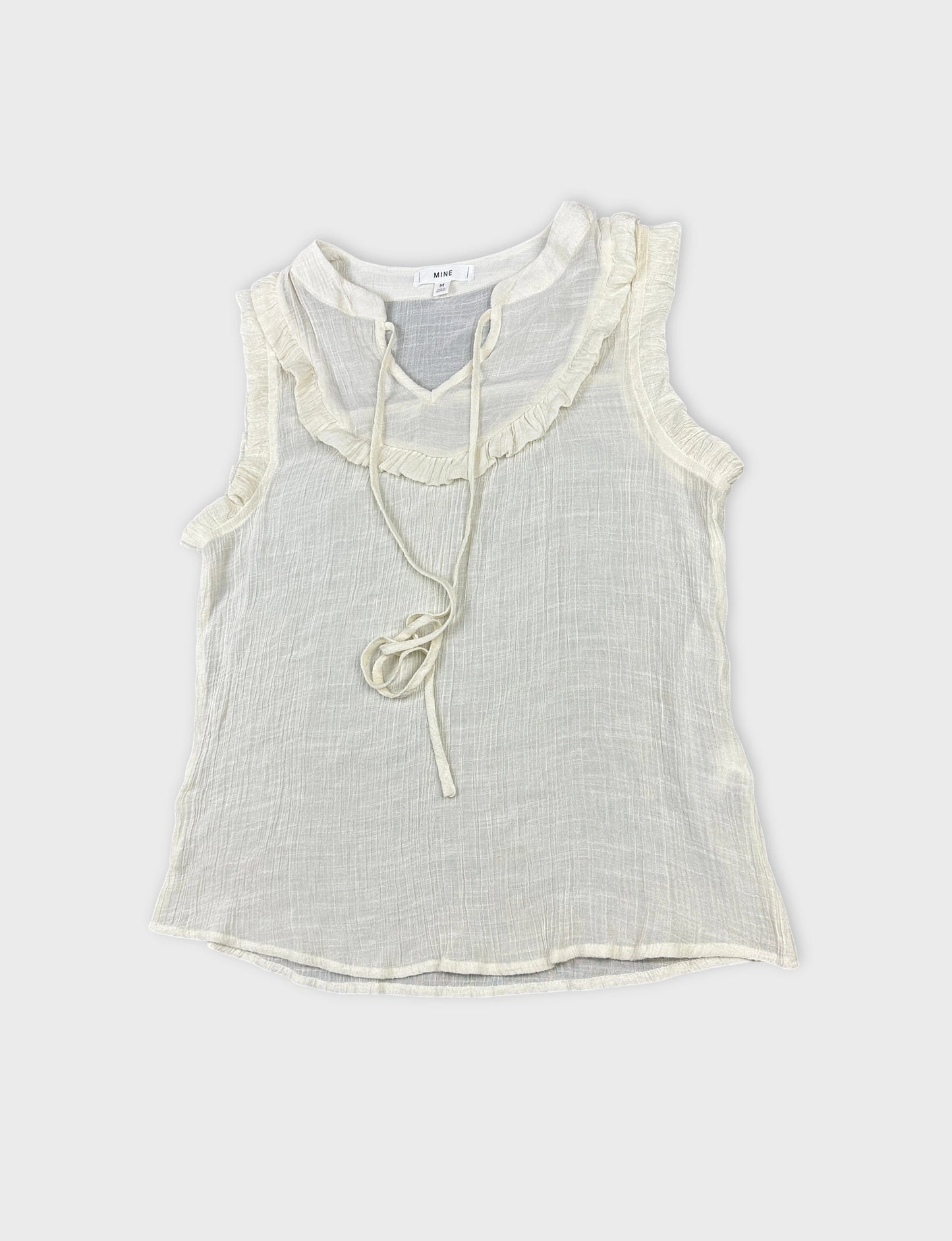 Detail view of a vintage women's short sleeve top in light cream with ruffled trim.