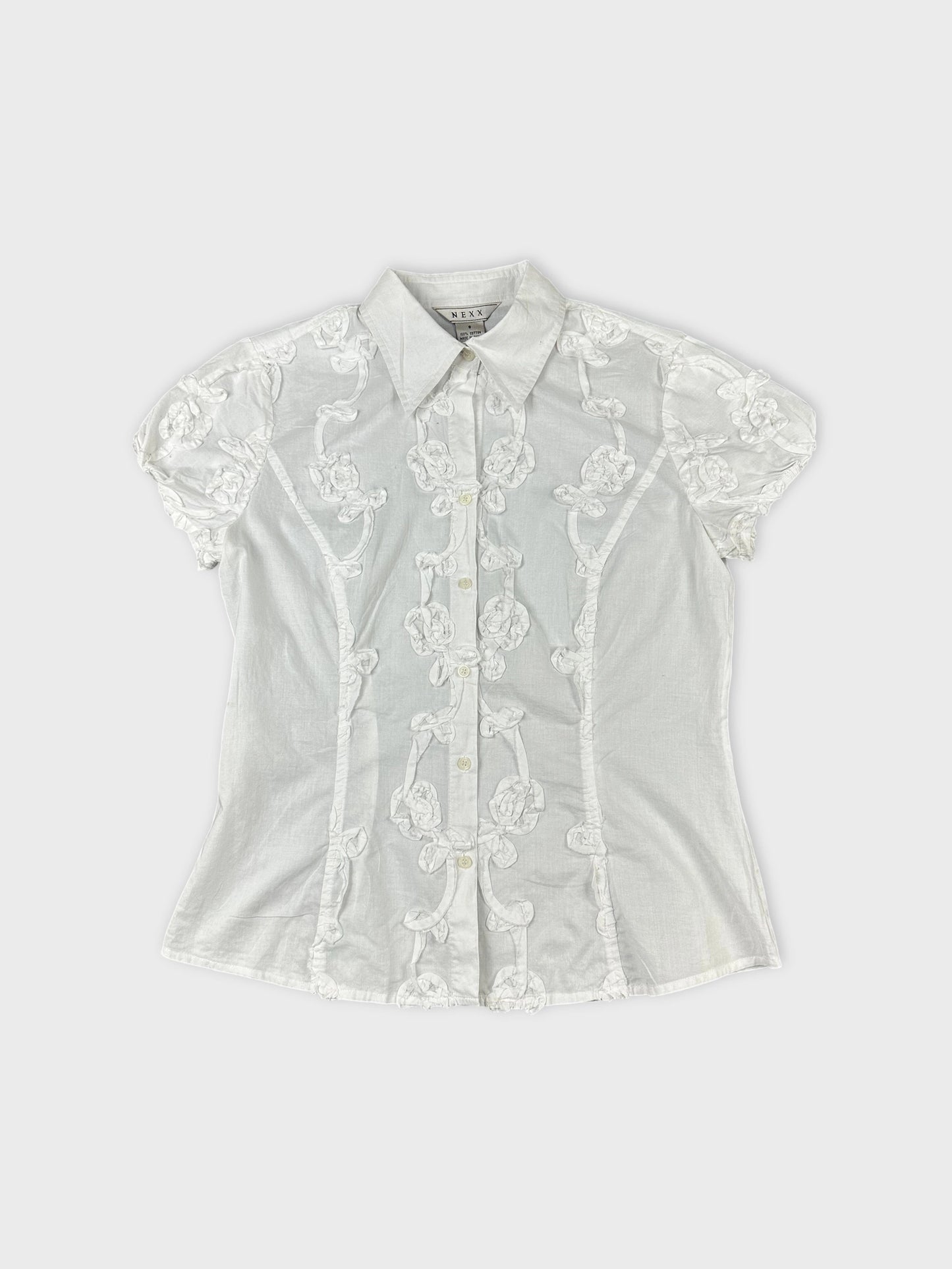 Front view of a vintage short sleeve top in white with floral embroidered details.