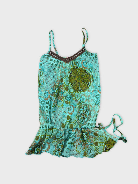 Front view of a turquoise women's top featuring floral prints and ruffled hem.