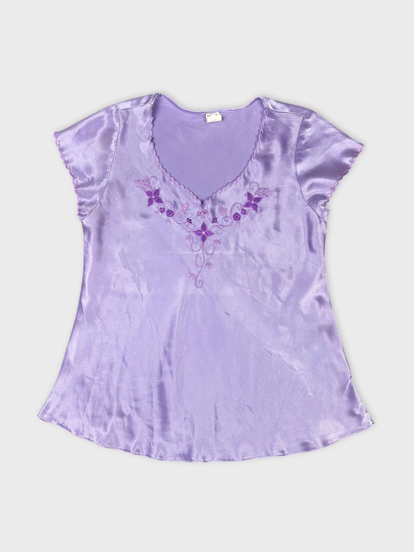 Front view of a lavender short sleeve top with floral embroidery.