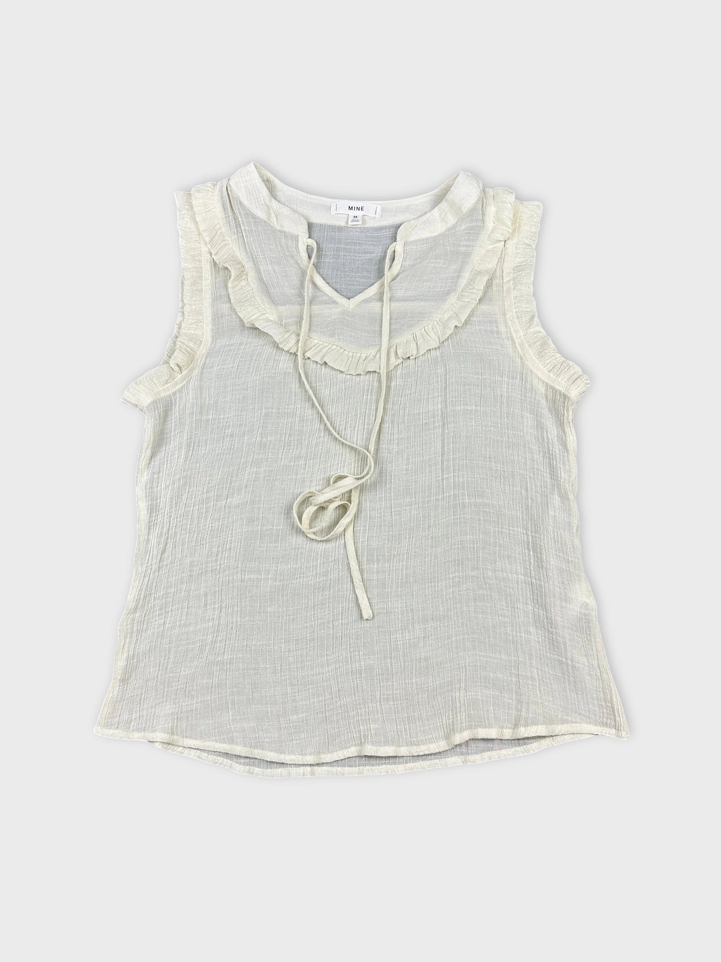 Front view of a vintage cream top with ruffled trim and drawstring.