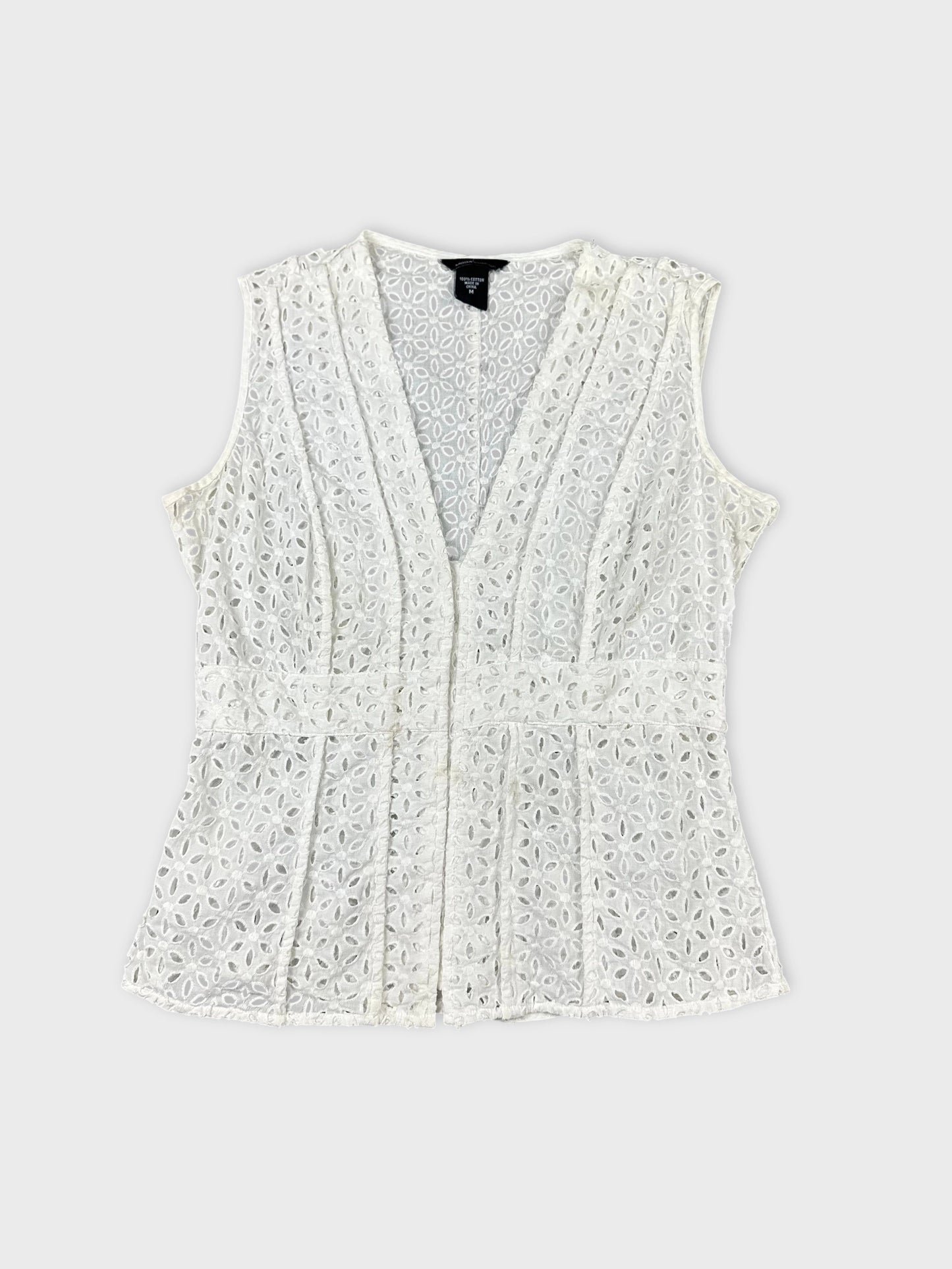 Front view of a white sleeveless top with floral lace pattern.