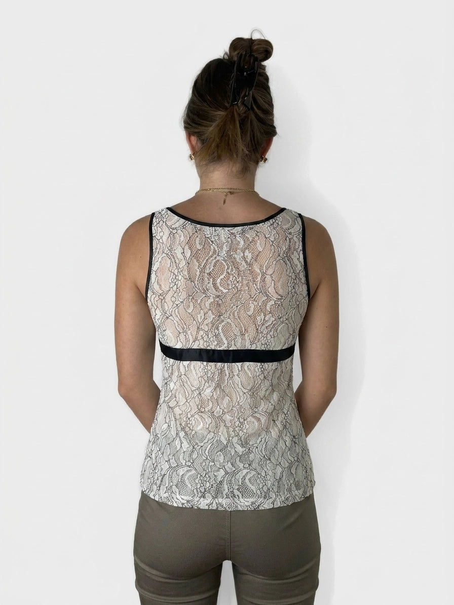 Back view of a women's lace top in cream with a black trim.