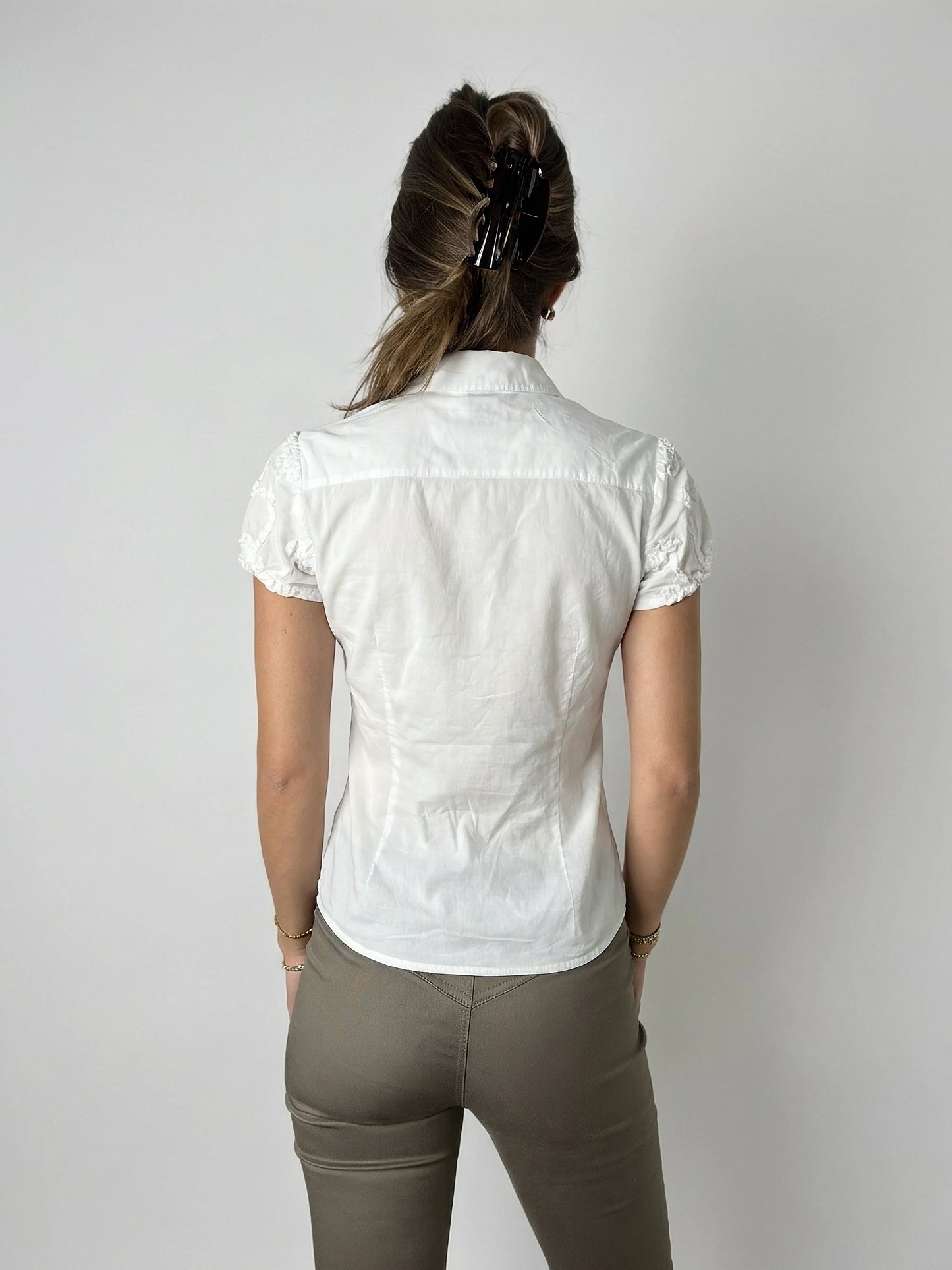 Back view of a white short sleeve top featuring delicate lace trim.