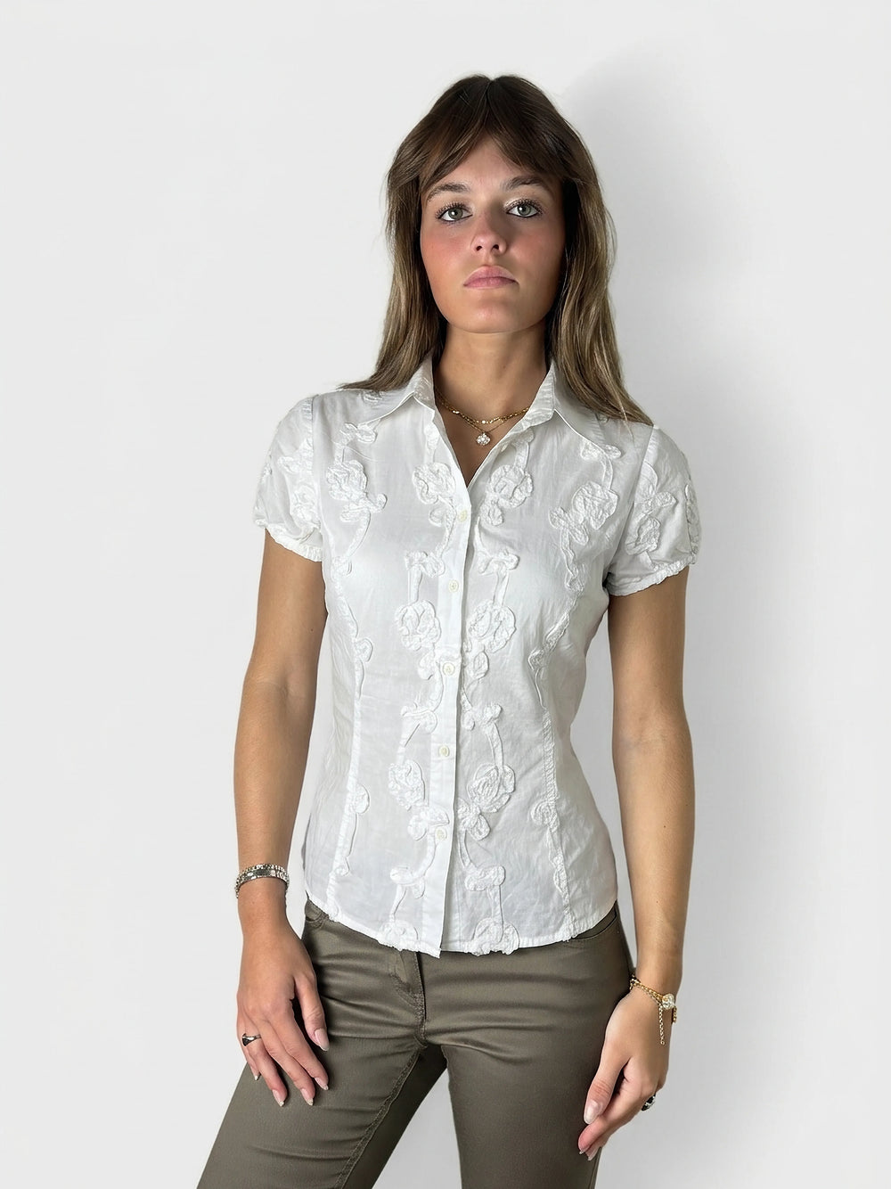 Front view of a white short-sleeve top with floral embroidery.