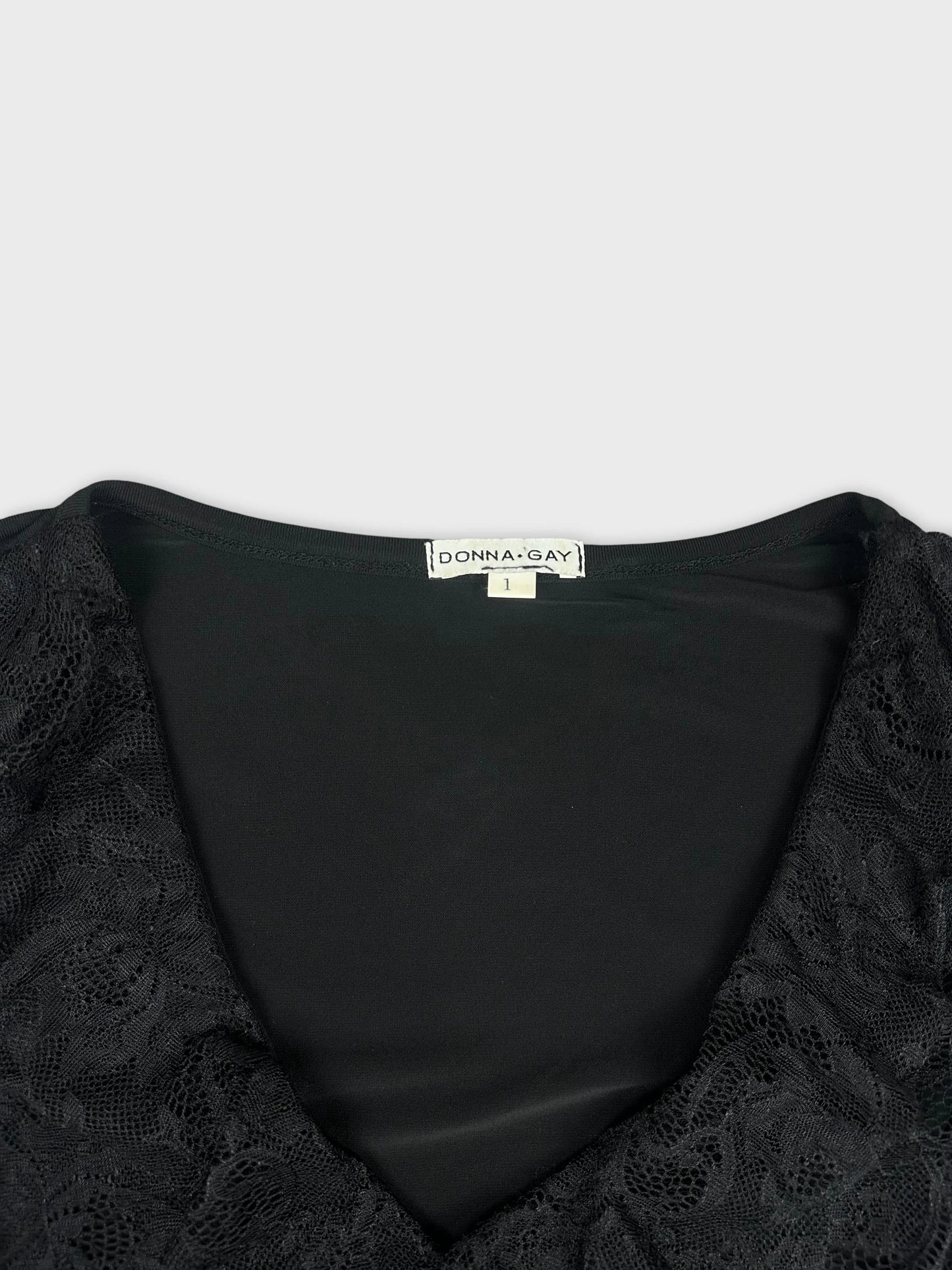 Detail view of a black top with lace trim around the neckline.