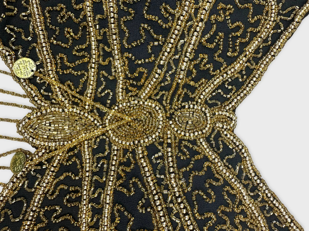Detail view of black shorts featuring intricate gold beaded patterns.