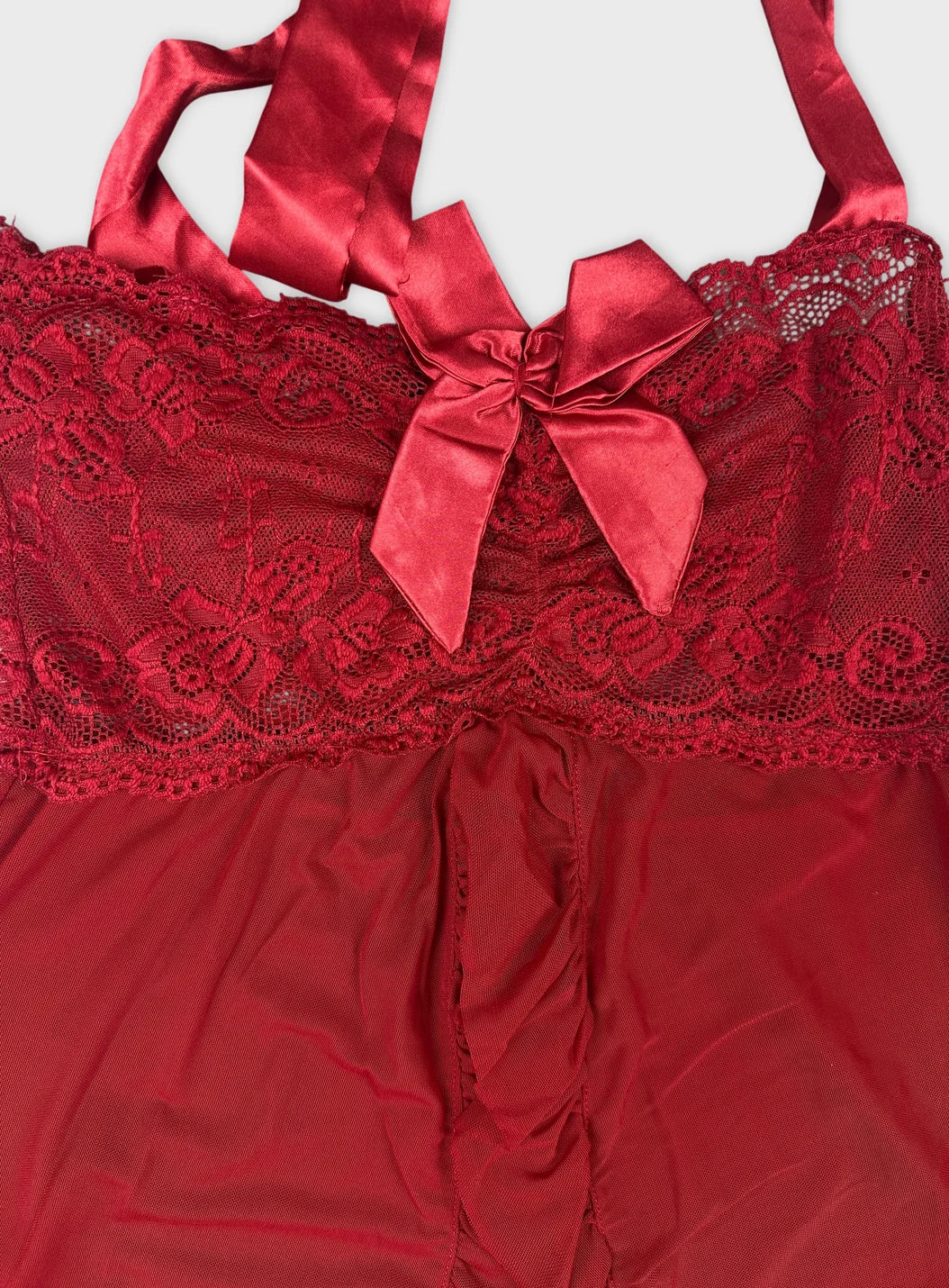 Detail view of red lace and satin women's top featuring a bow.