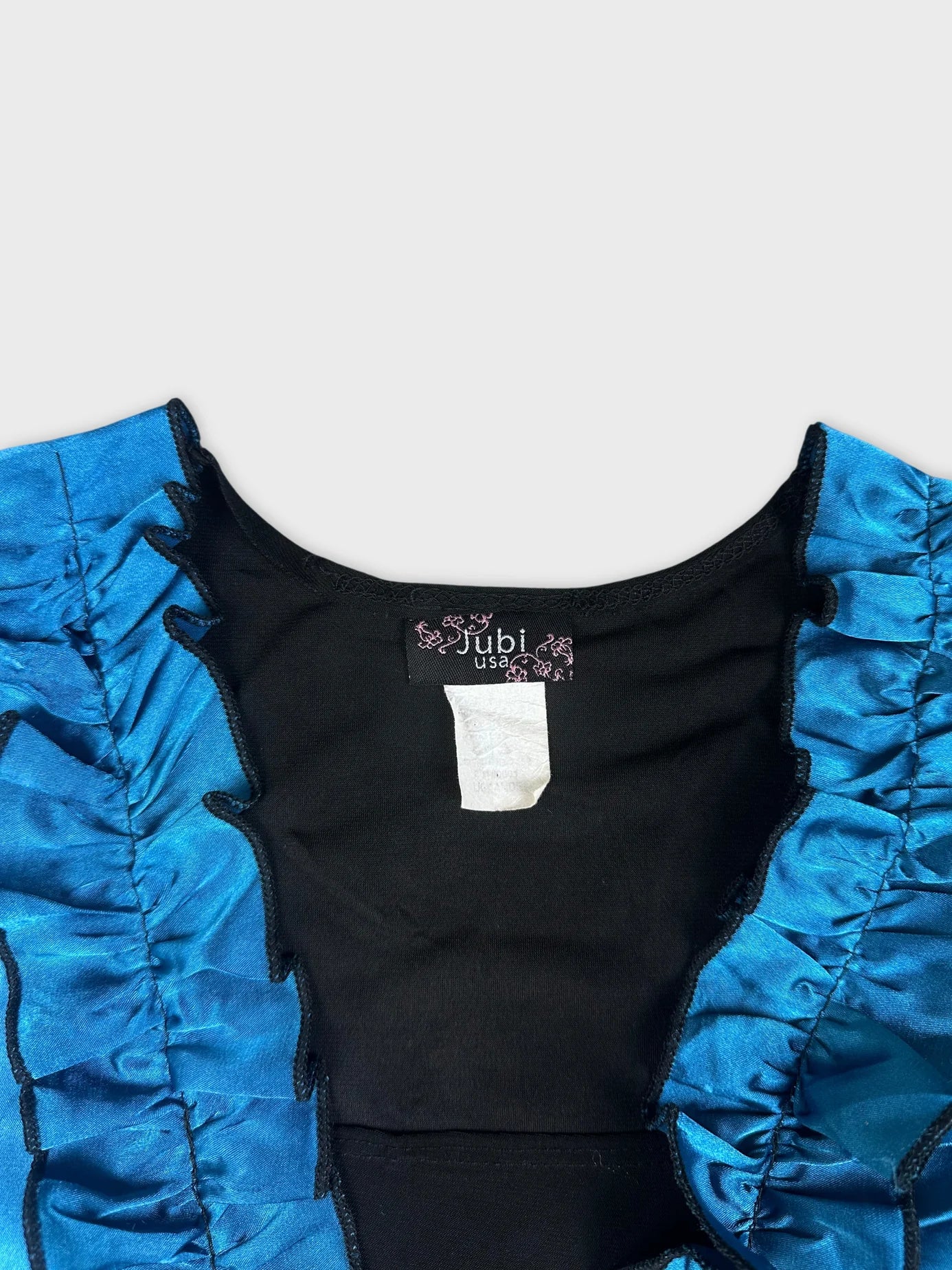 Detail view of black top with blue ruffled neckline.