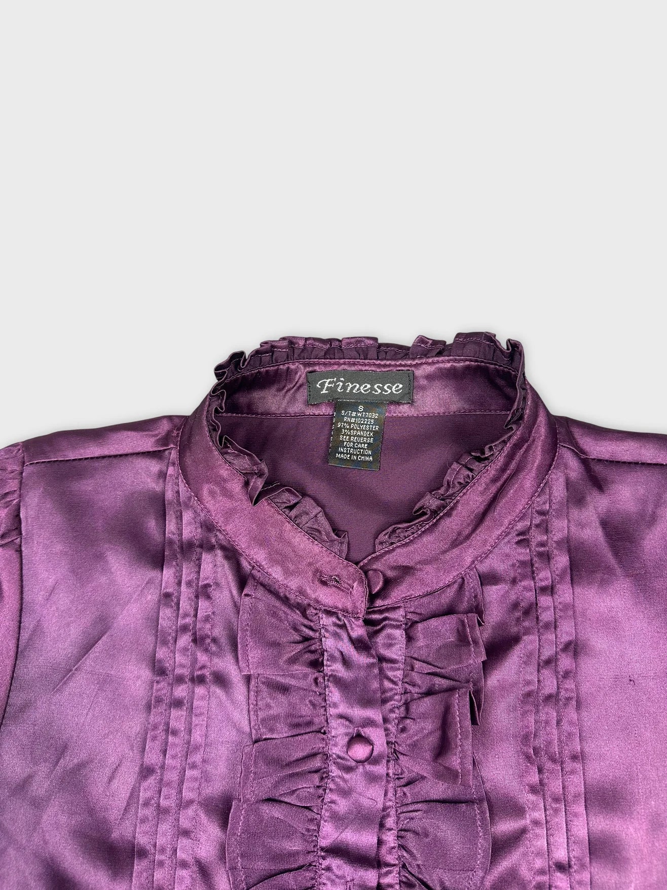 Detail view of a women's button-up shirt in purple with ruffled trim