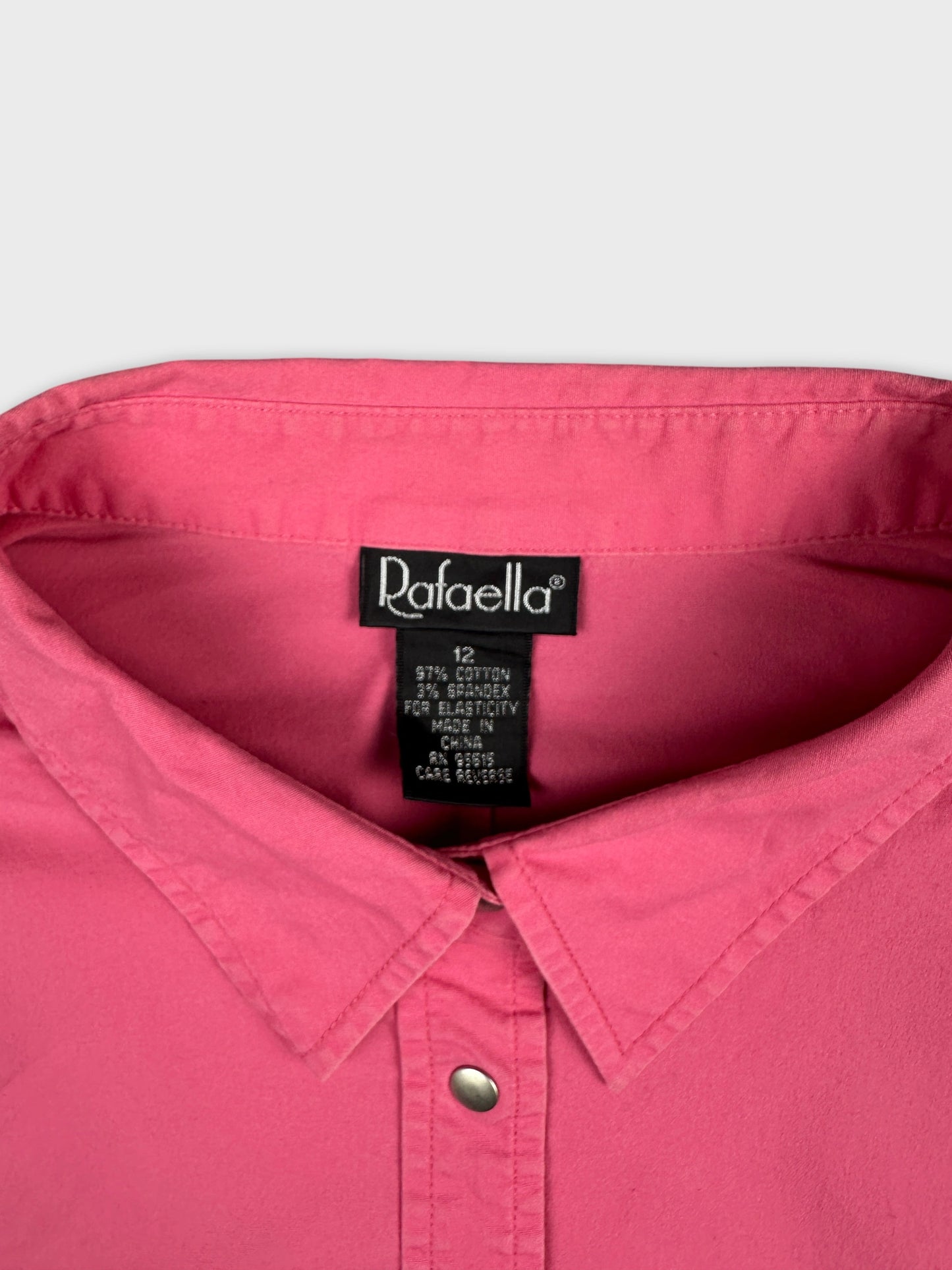 Detail view of a pink button-up shirt with a classic collar.