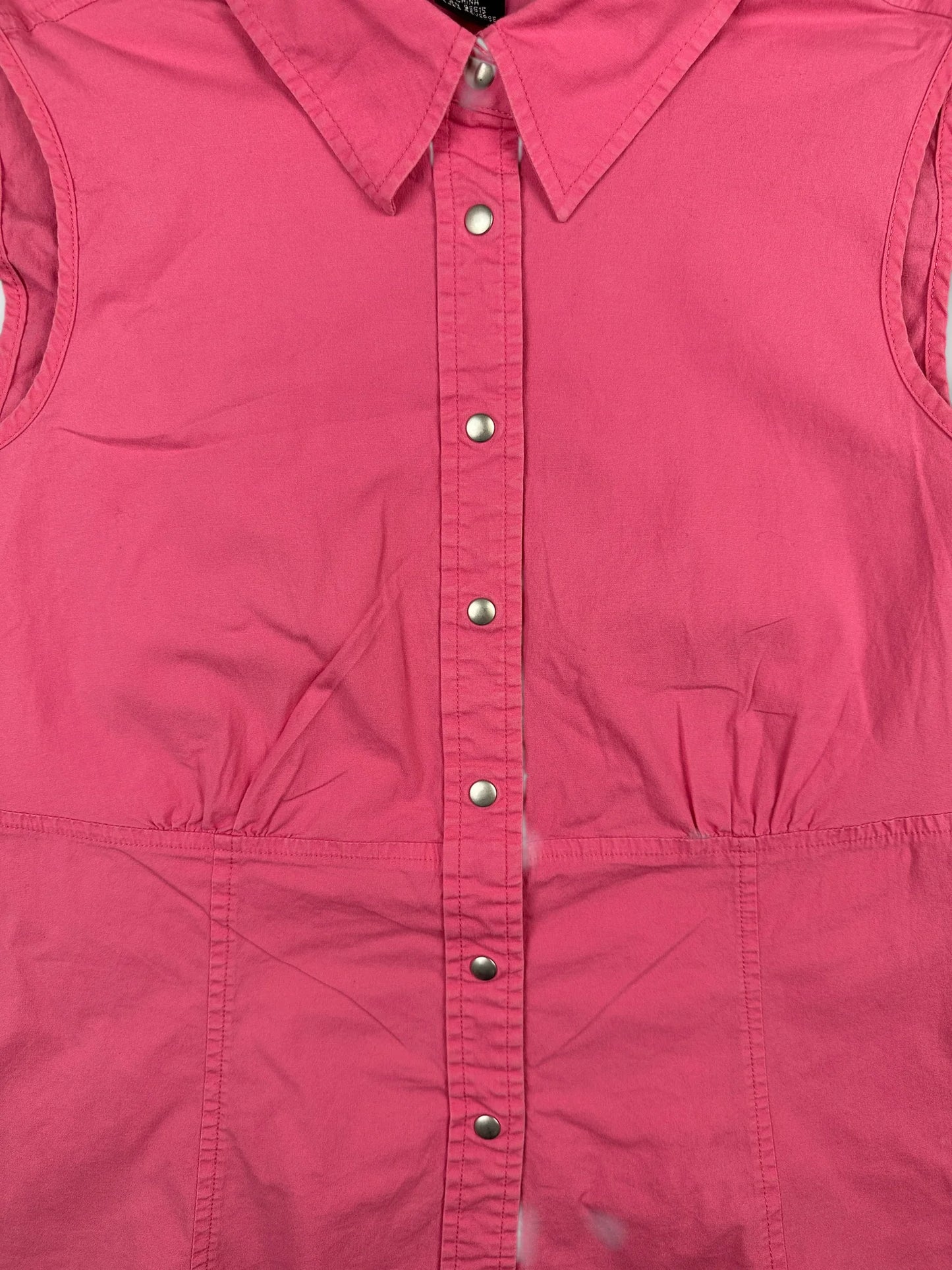 detail view of a pink button-up shirt featuring snap buttons and a collar