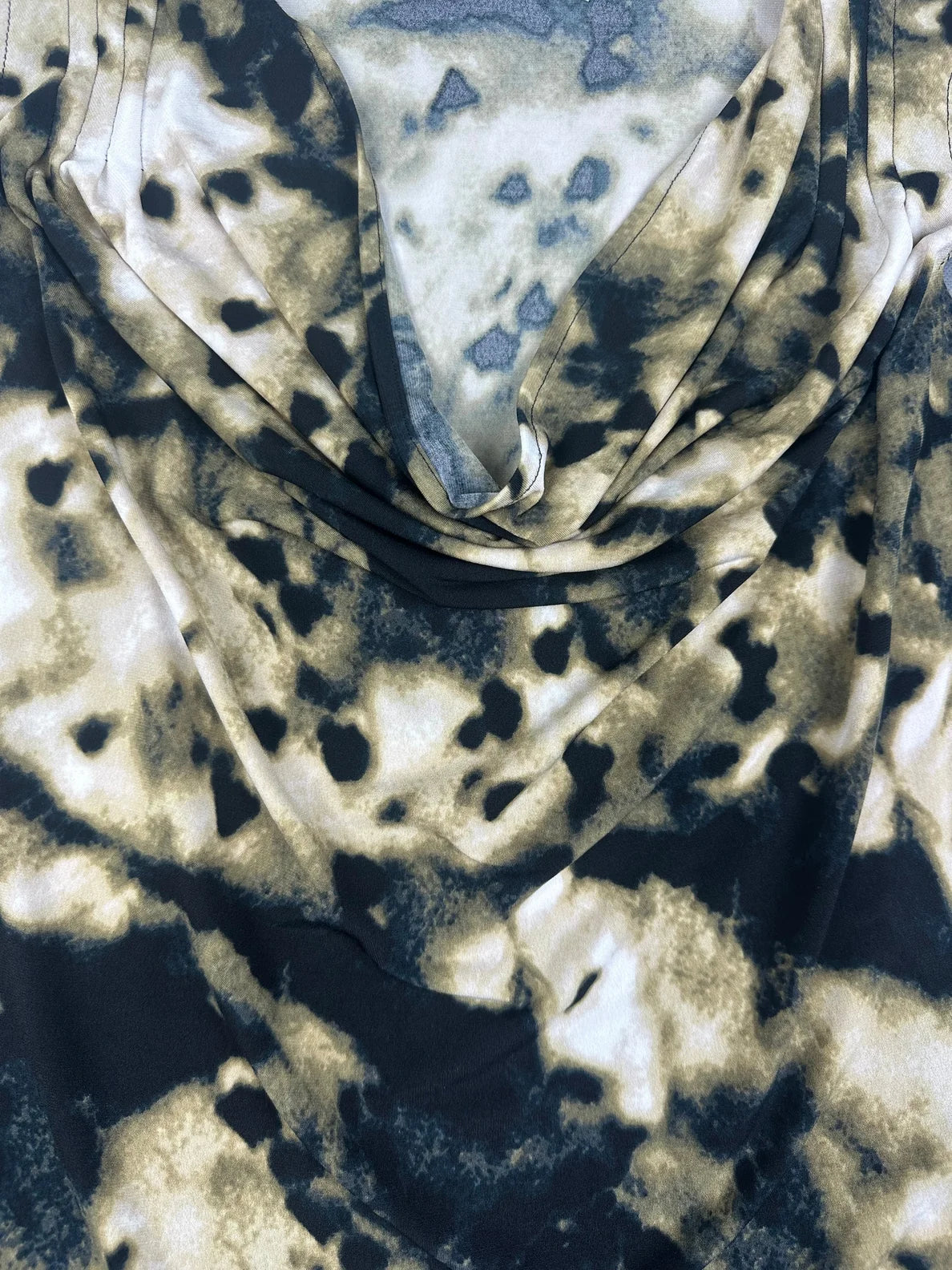 Detail view of a short sleeve top in beige and black abstract print.