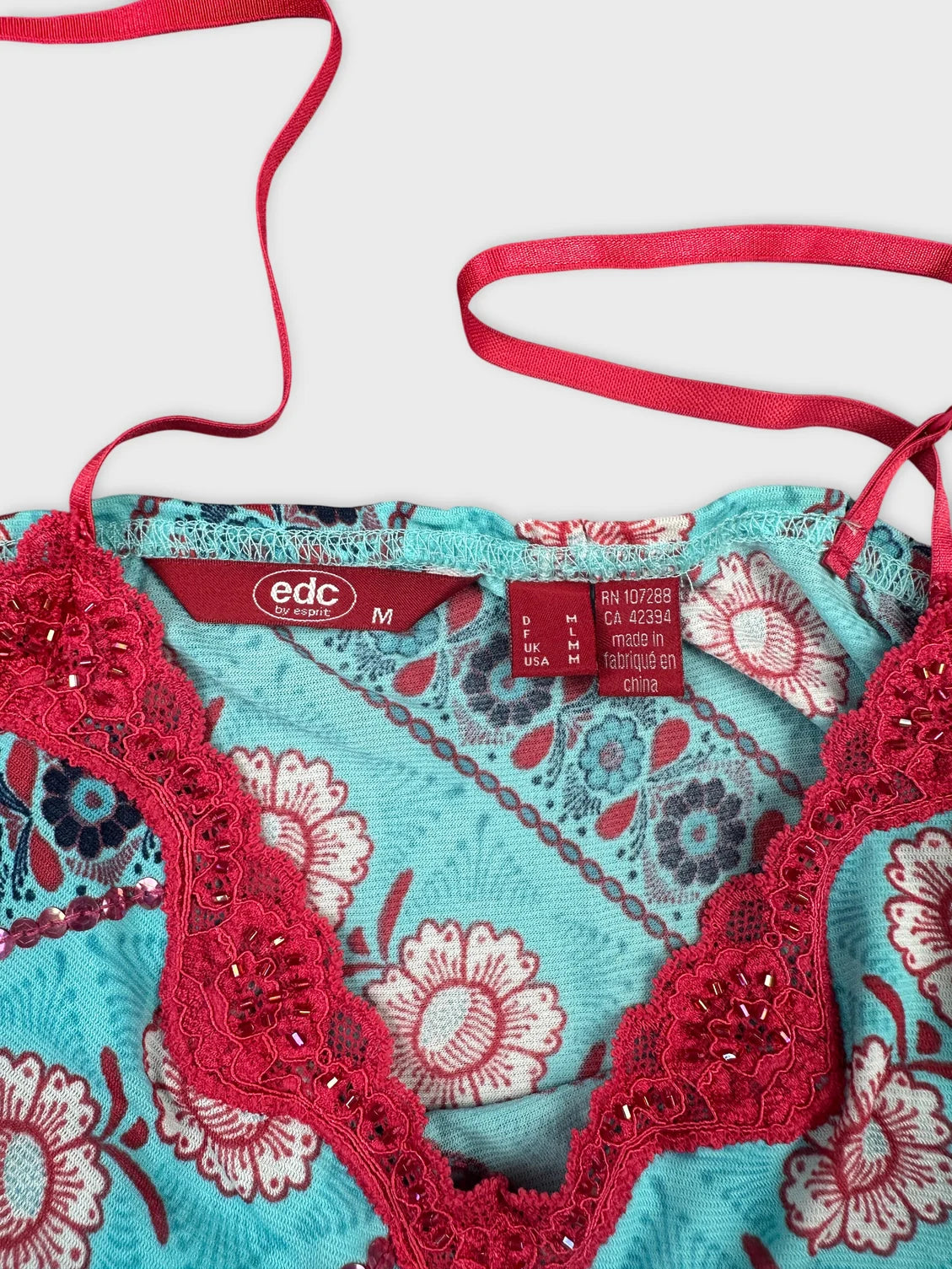 Detail view of upper body shorts featuring turquoise fabric and floral lace trim.