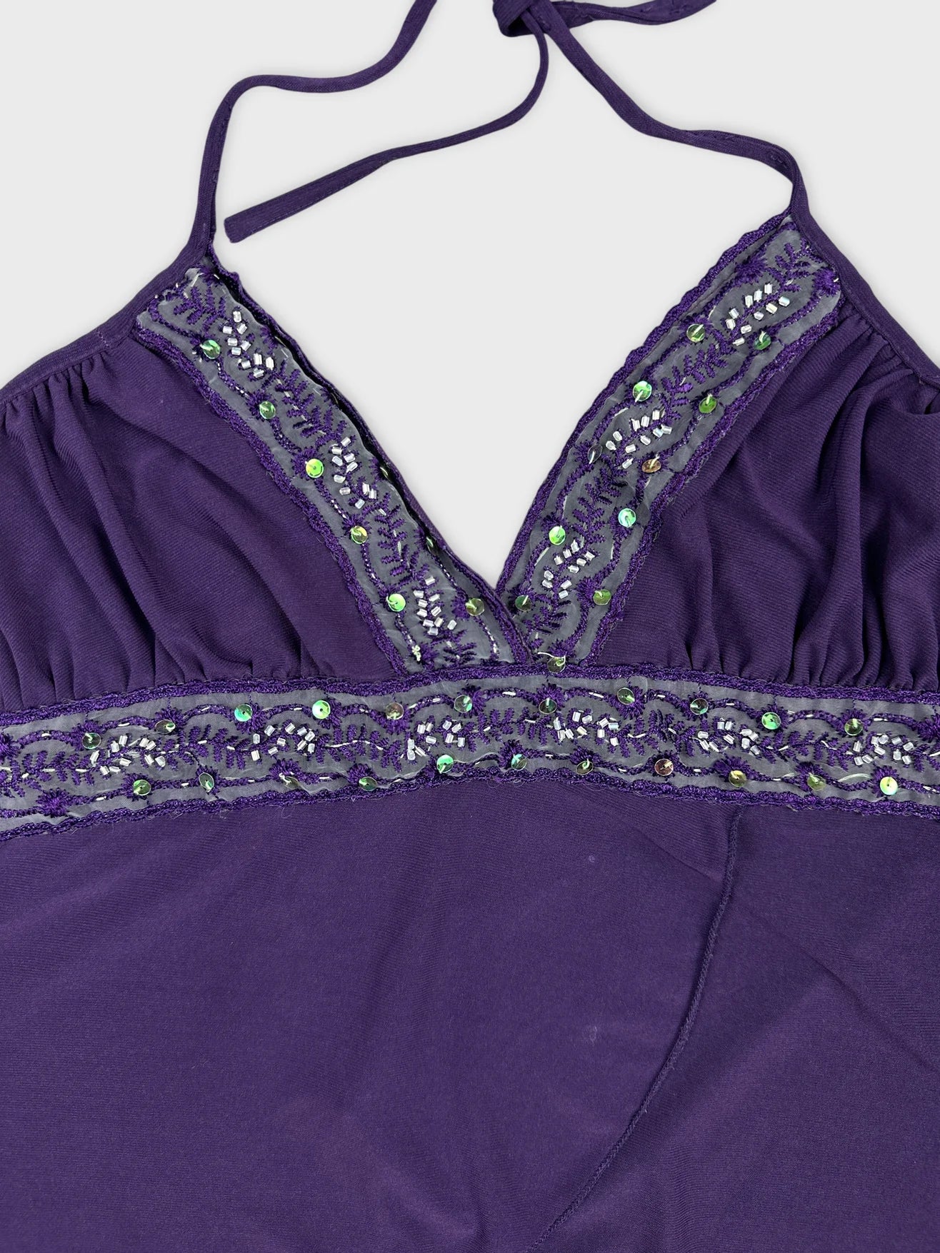 Detail view of purple women upper body shorts with embellished neckline.