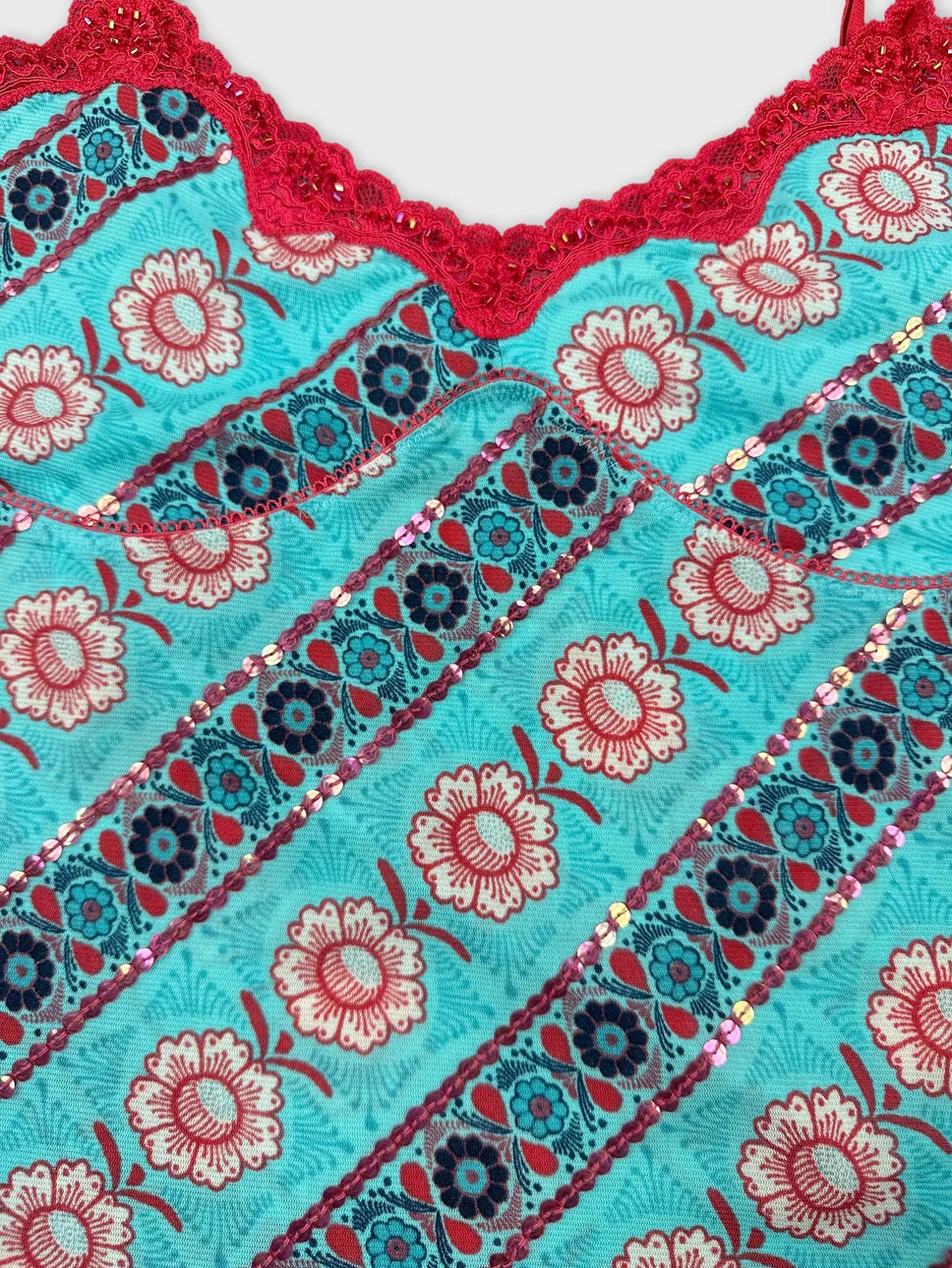 Detail view of turquoise upper body shorts with red lace trim and floral pattern.