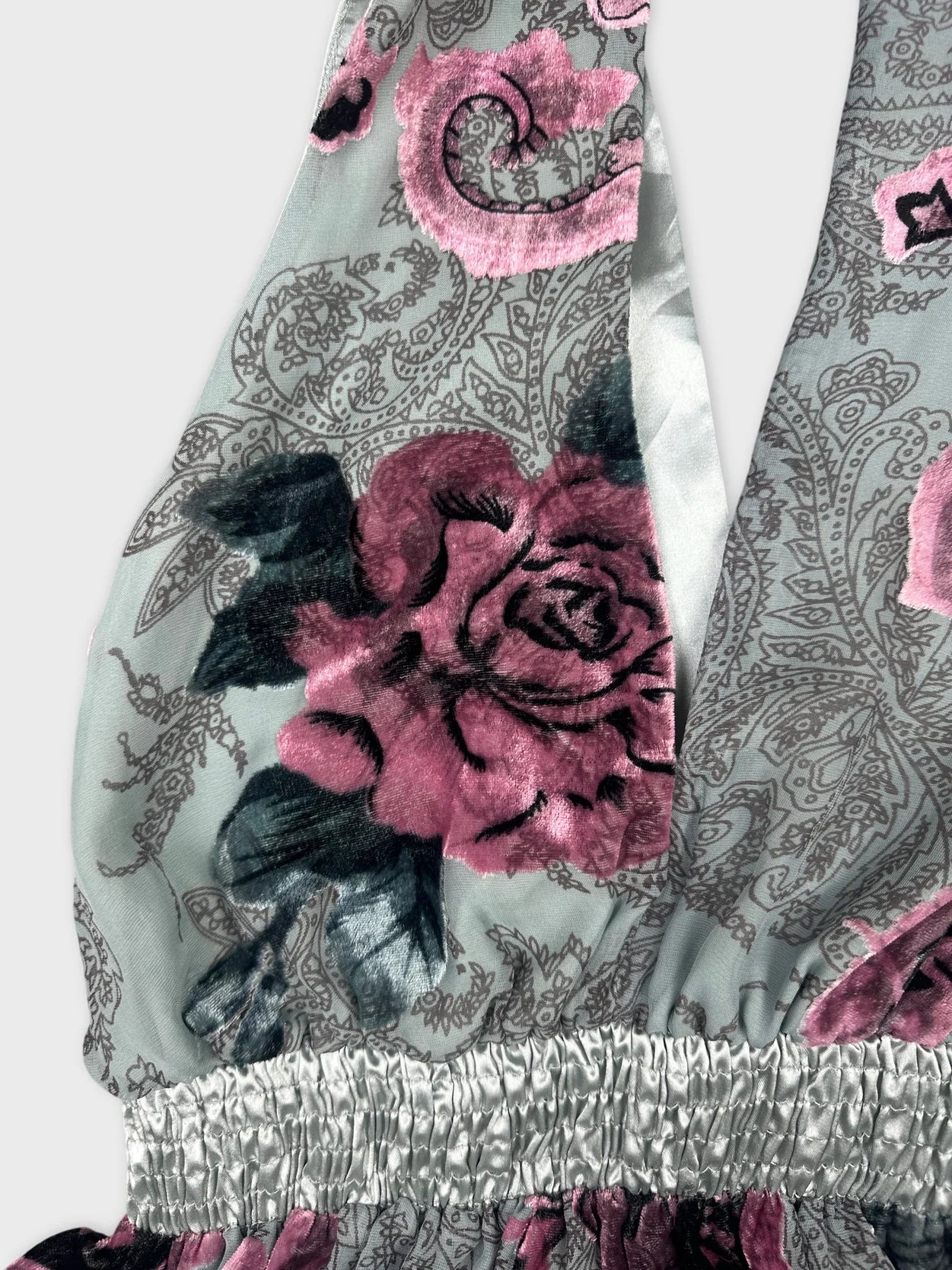 Detail view of a sleeveless floral vintage top in muted gray and pink.