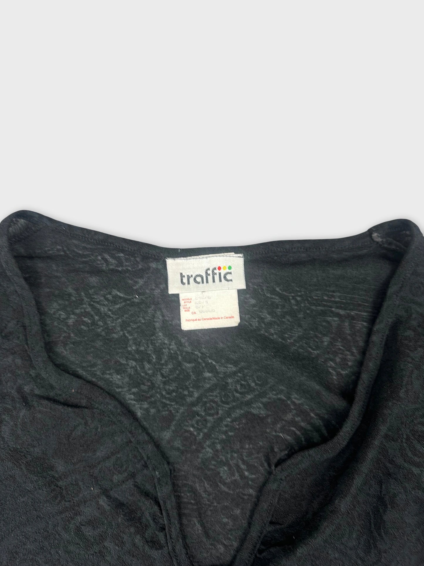 Detail view of black long sleeve top featuring subtle floral pattern.