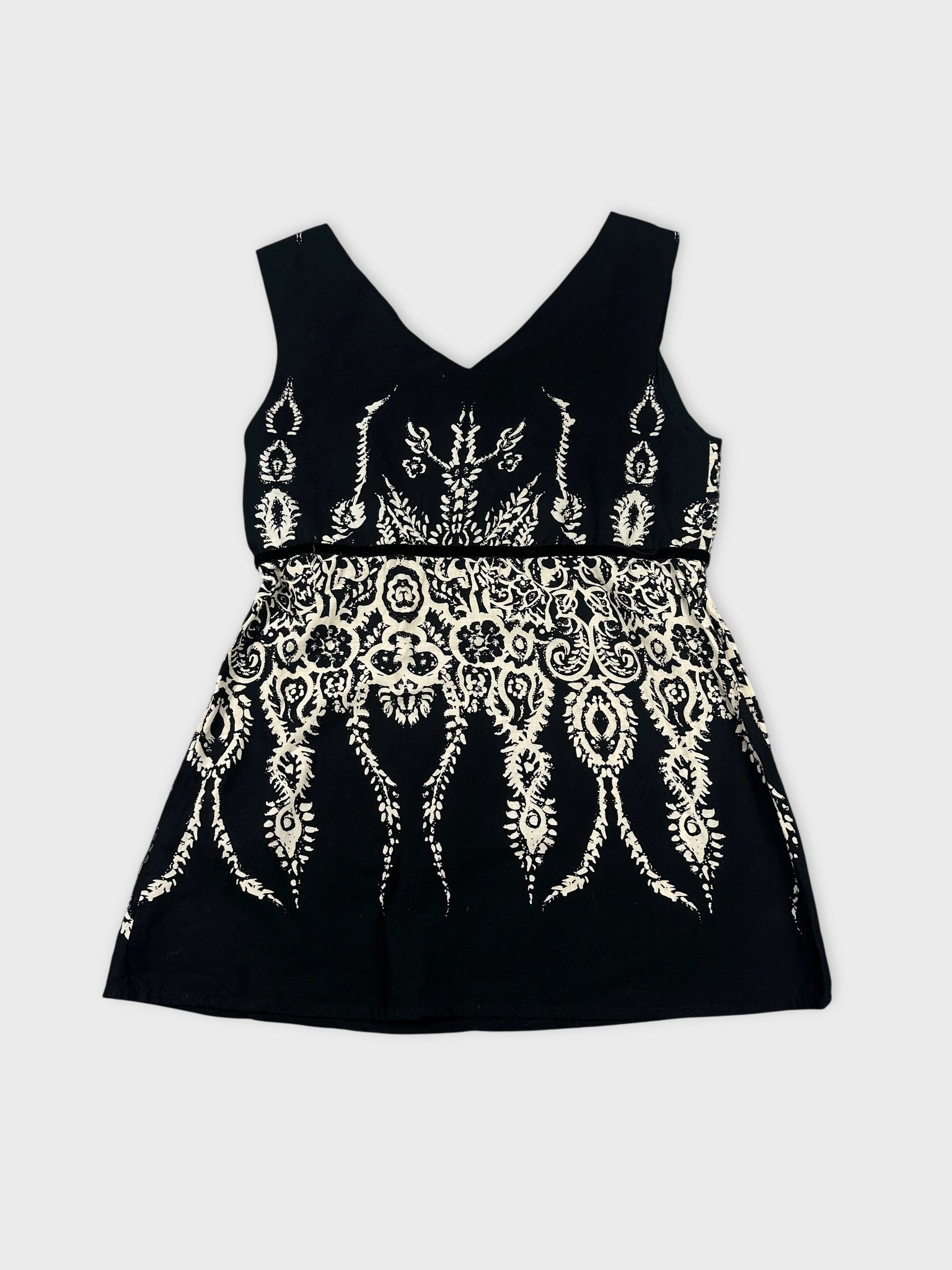 Back view of a black sleeveless top with white intricate print.