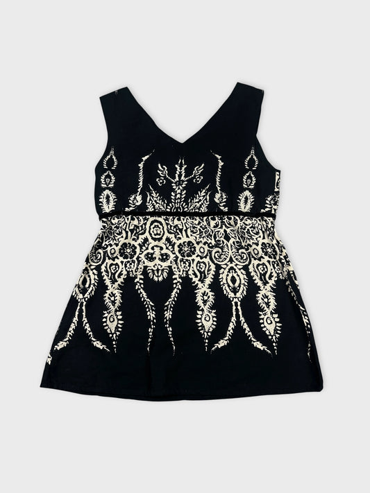 Back view of a black sleeveless top with white intricate print.