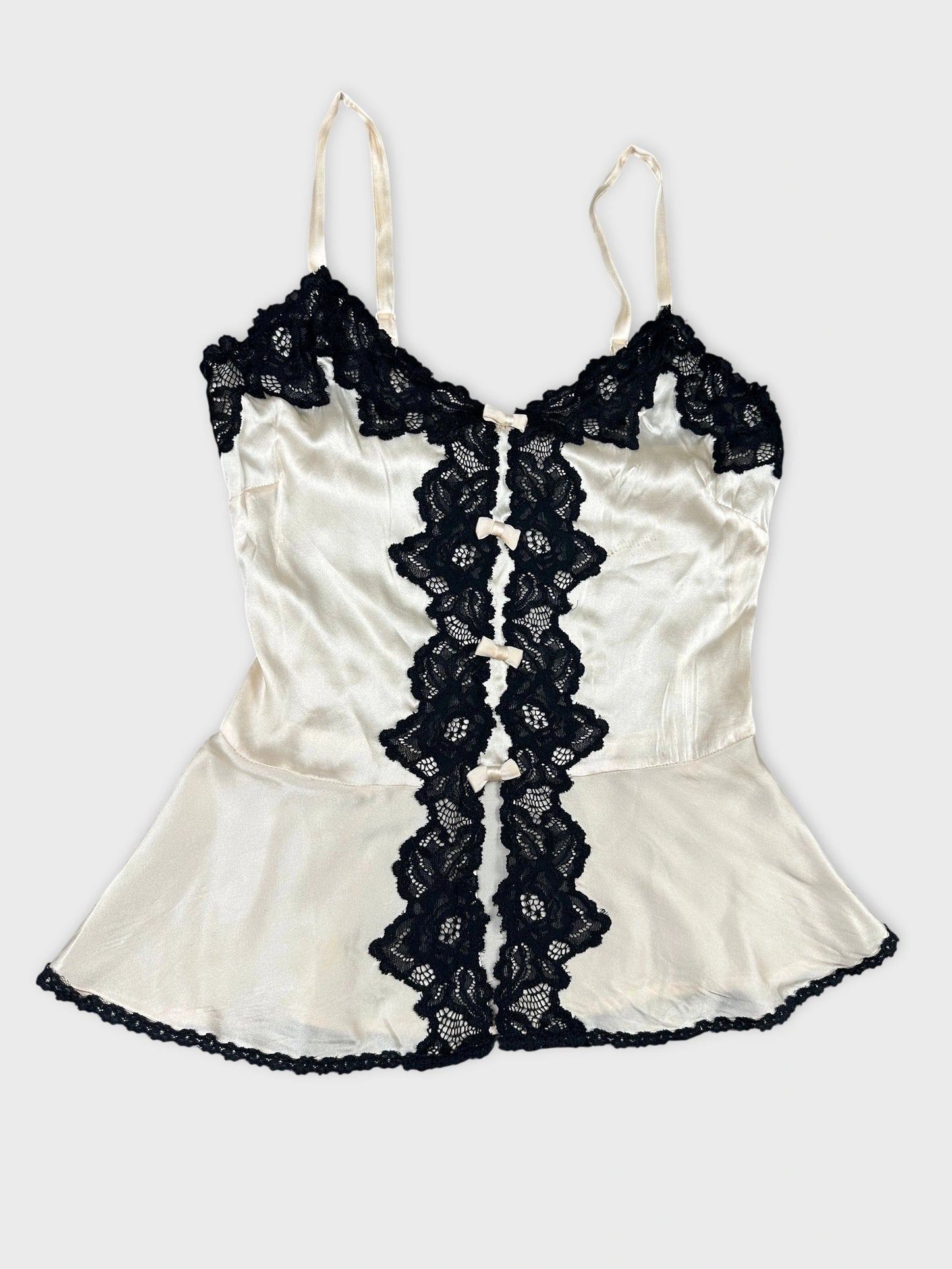 Back view of a cream satin top with black lace details.