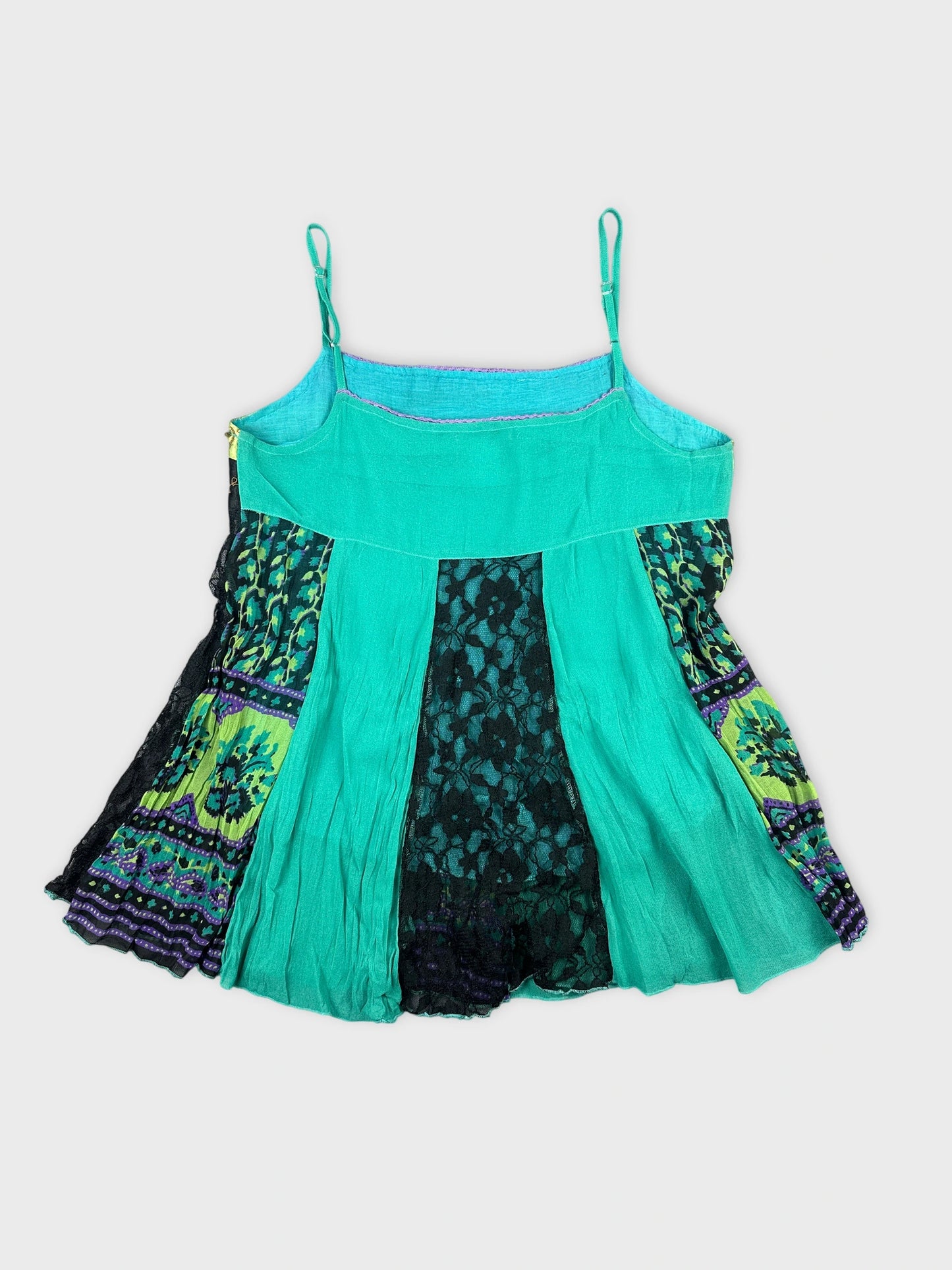 Back view of a turquoise top featuring lace and patterned panels.