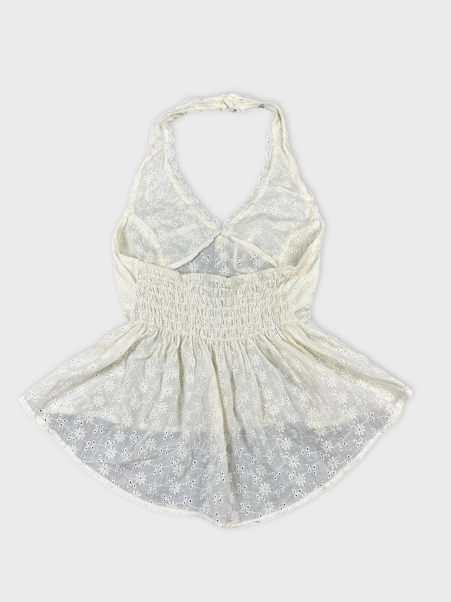 Back view of a white vintage halter top with floral embroidery.