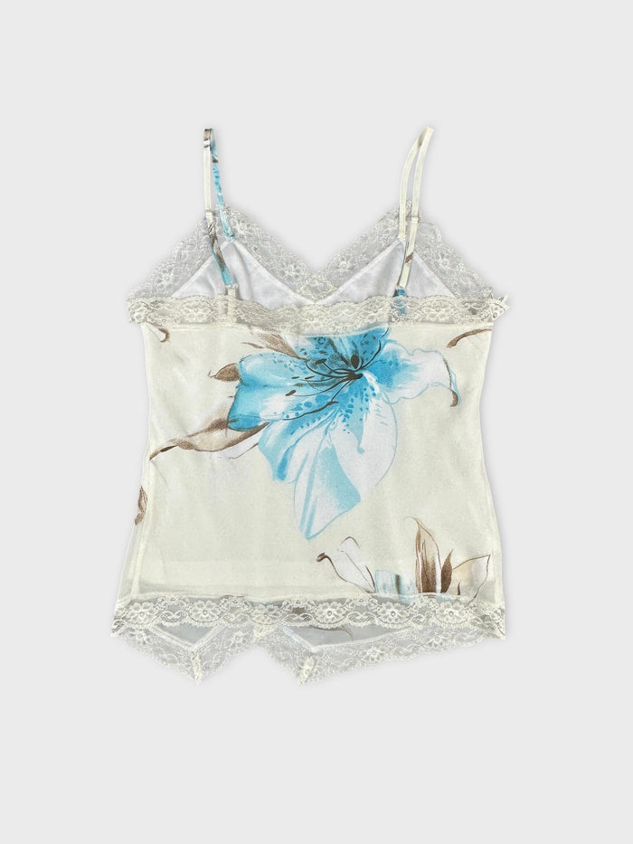 Back view of a spaghetti strap top in cream with floral print and lace trim.